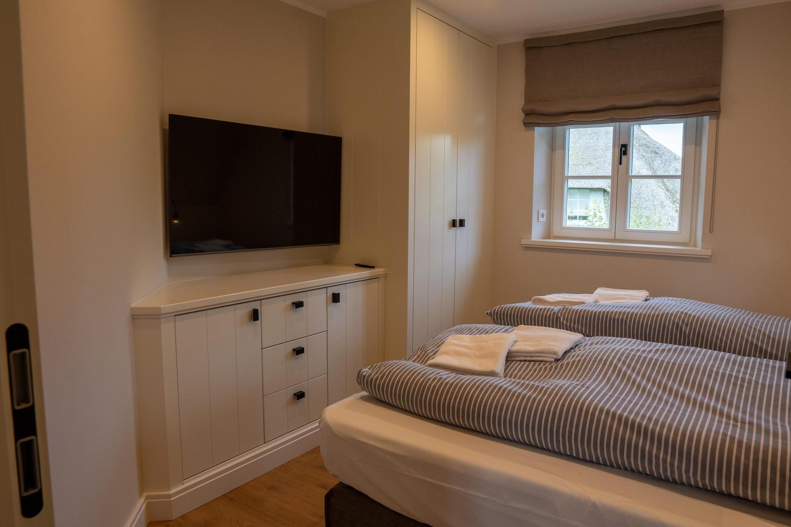 Zimmer mit zwei Betten, TV und Fenster mit Blick auf Dach