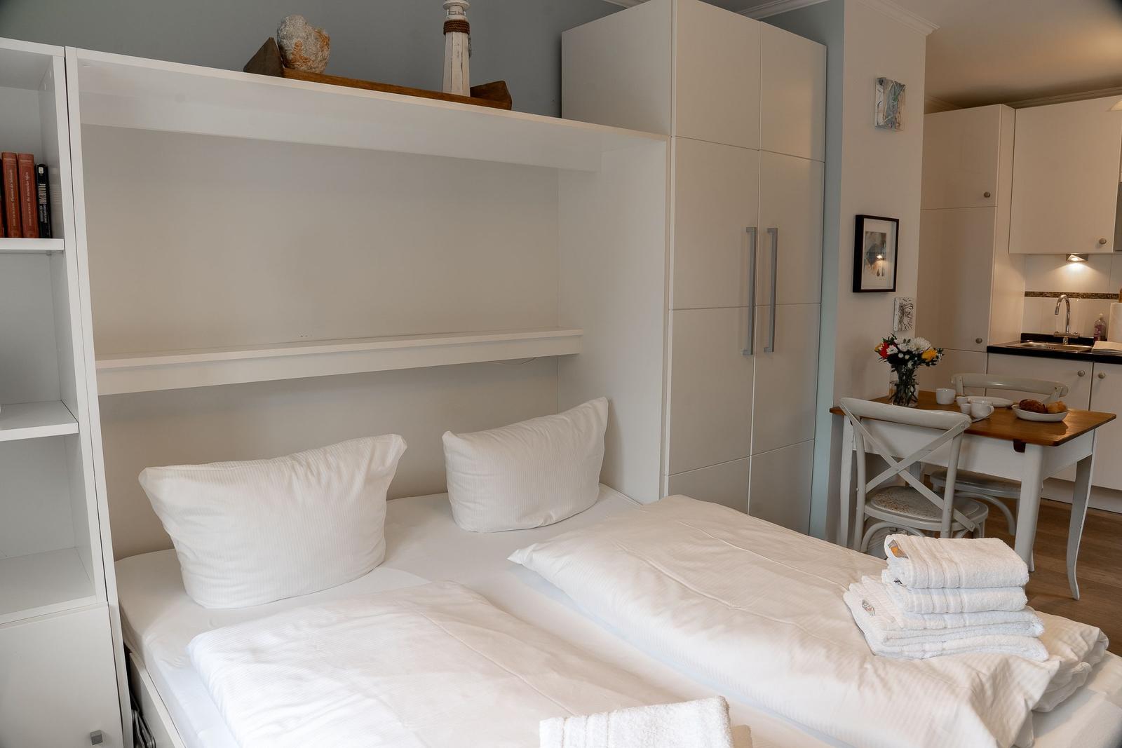 Schlafzimmer mit Bett, Schrank und kleinem Esstisch