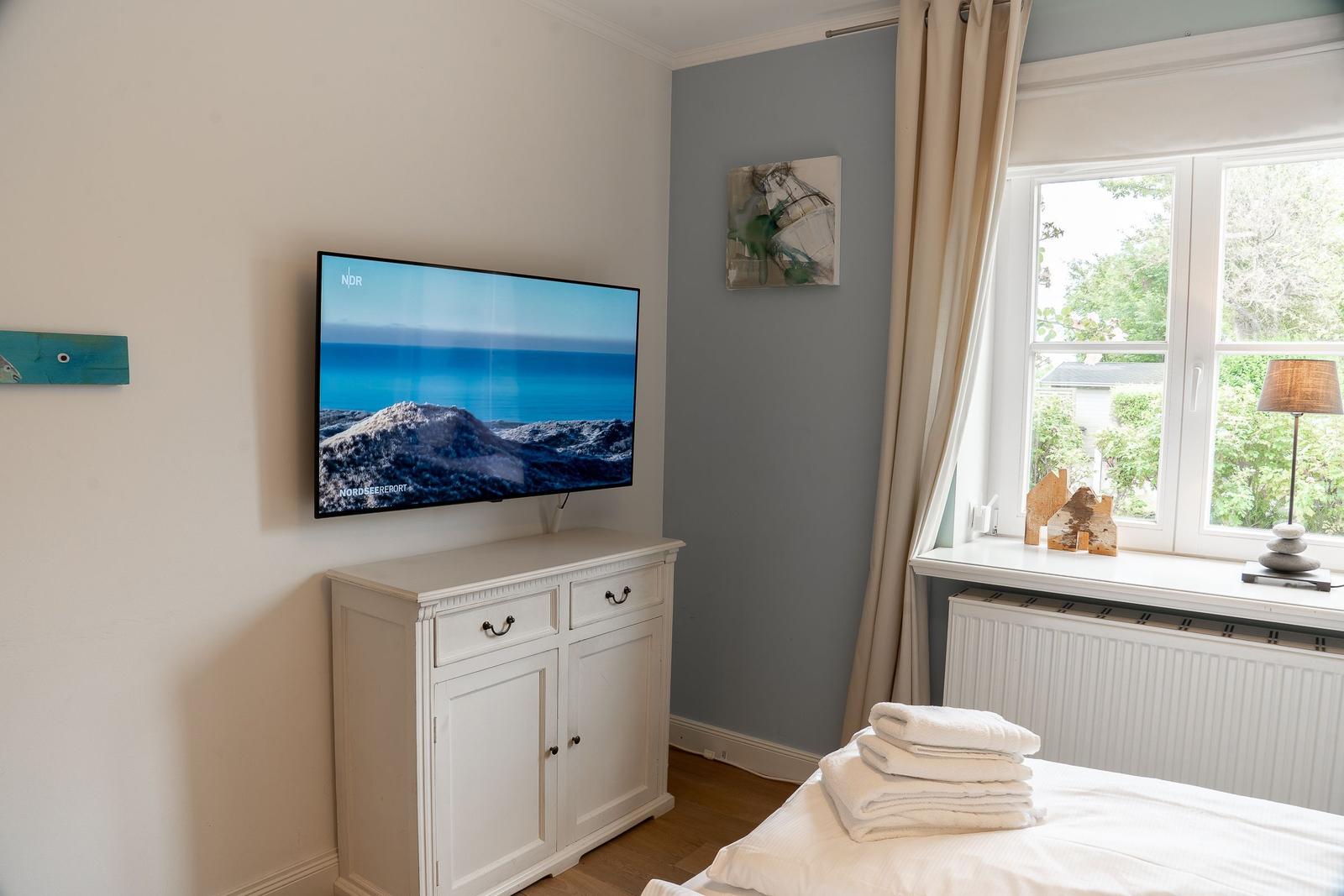 Schlafzimmer mit Fernseher, Fenster und Bett