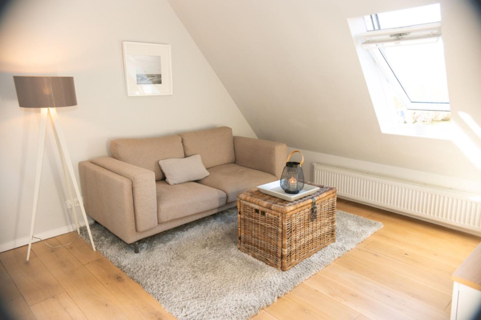 Ein Wohnzimmer mit Sofa, Korbtablett und Dachfenster.