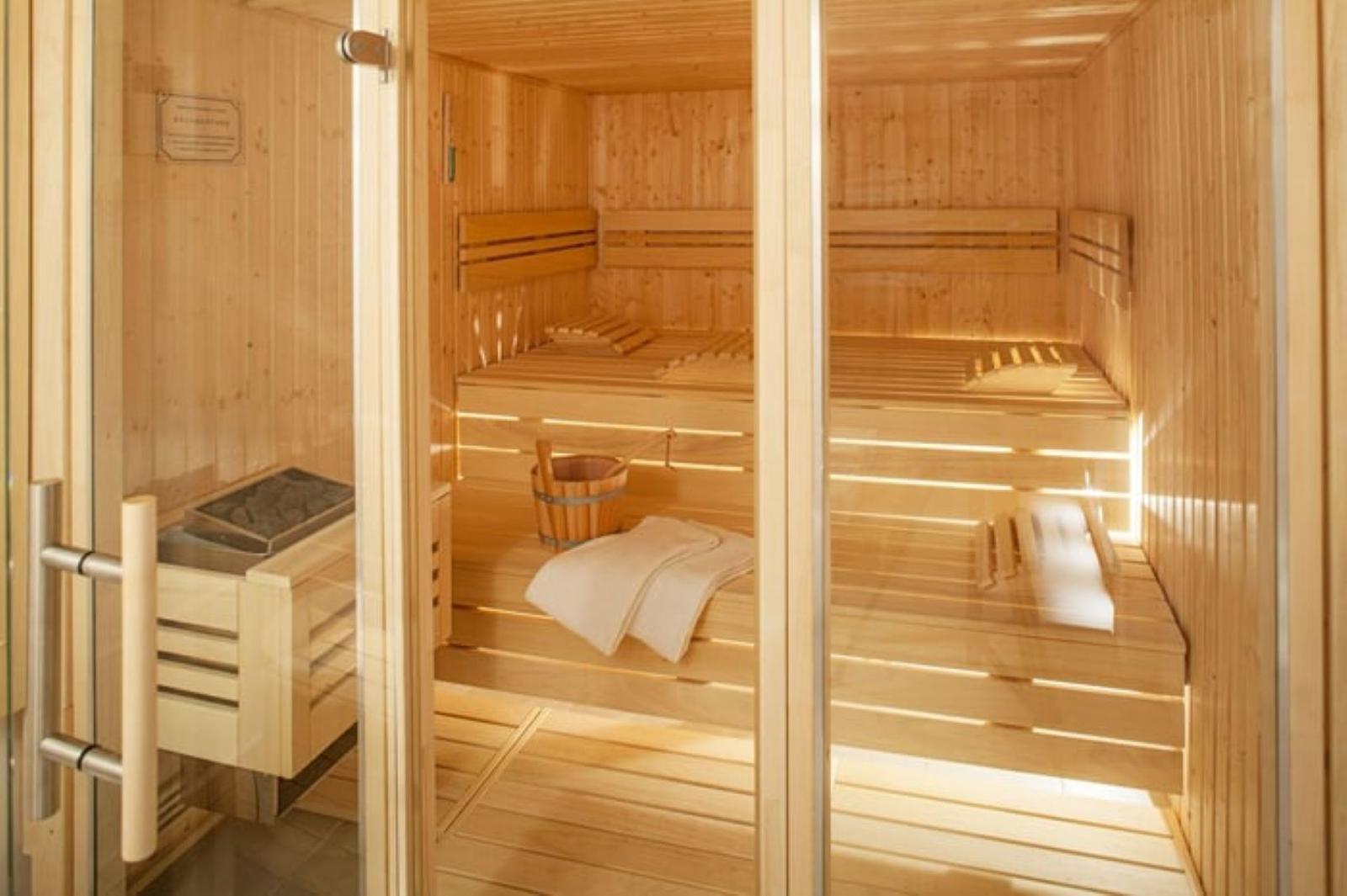 Holzsauna mit mehreren Sitzbänken und einem Eimer.