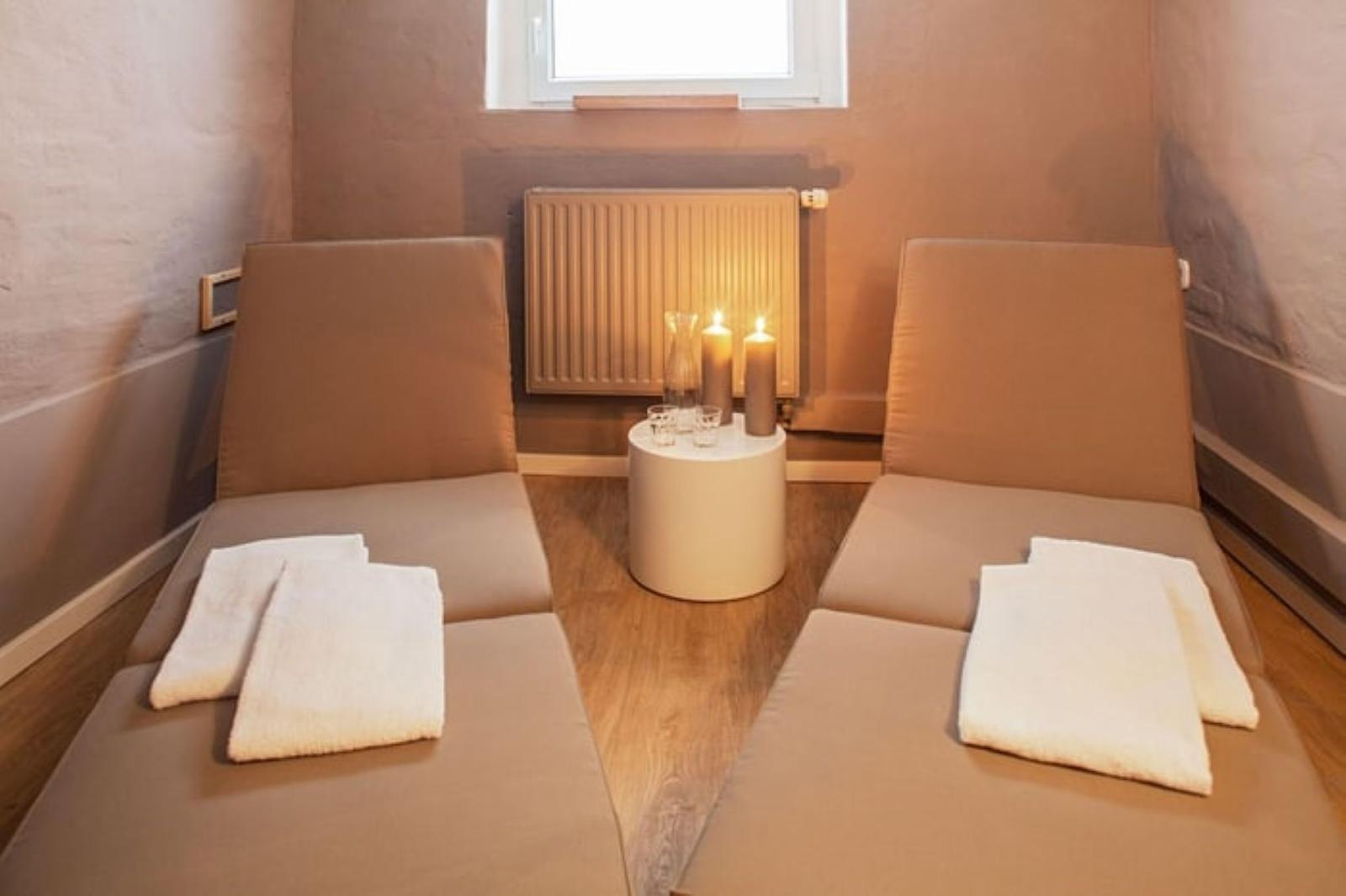 Zwei Liegen mit Handtüchern, Tisch mit Kerzen und Heizkörper an Wand