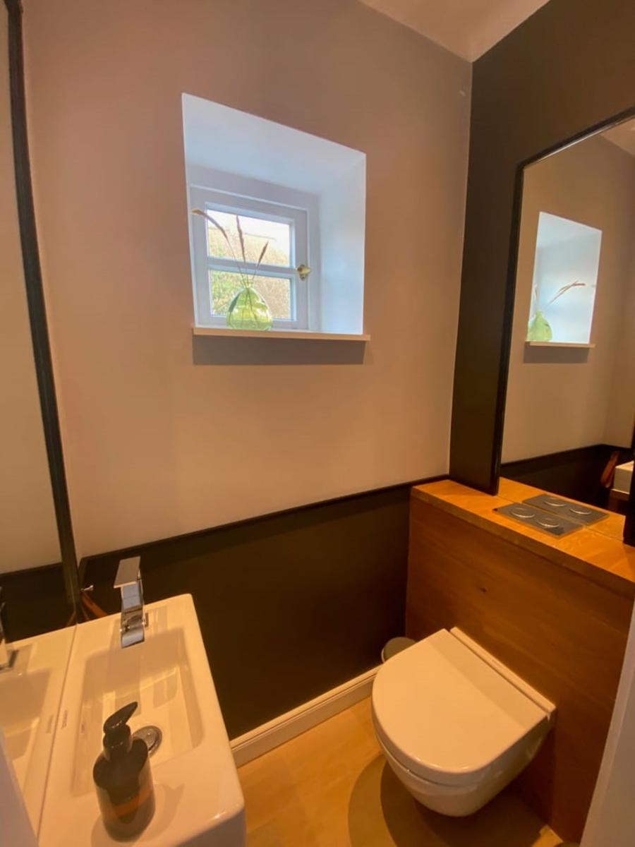 Badezimmer mit Waschbecken, Toilette und kleinem Fenster.