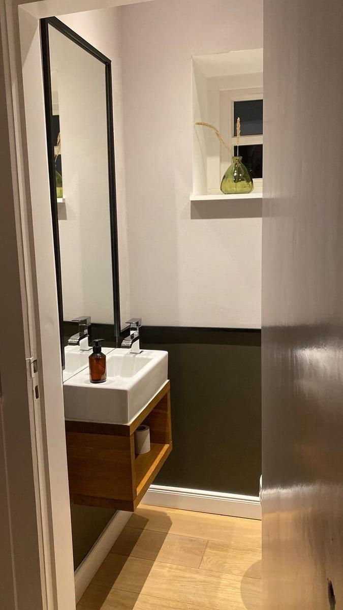 Badezimmer mit Waschbecken, Spiegel und Fenster