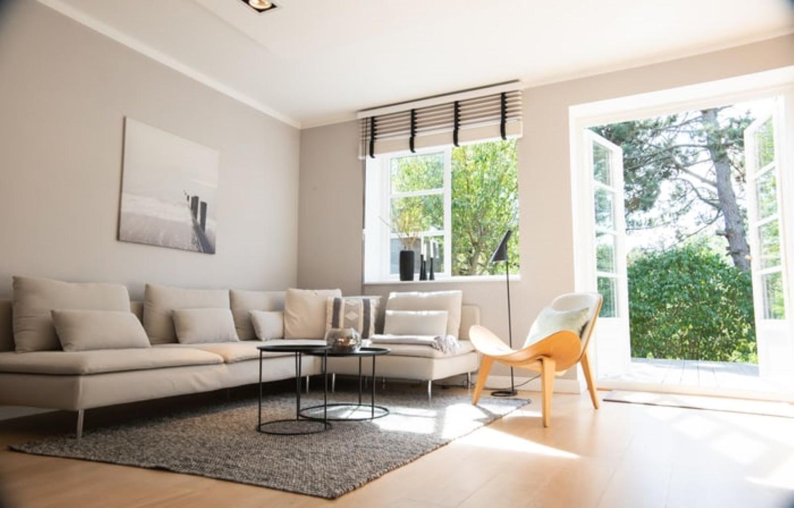 Wohnzimmer mit Sofa, Sessel und Blick auf Garten.