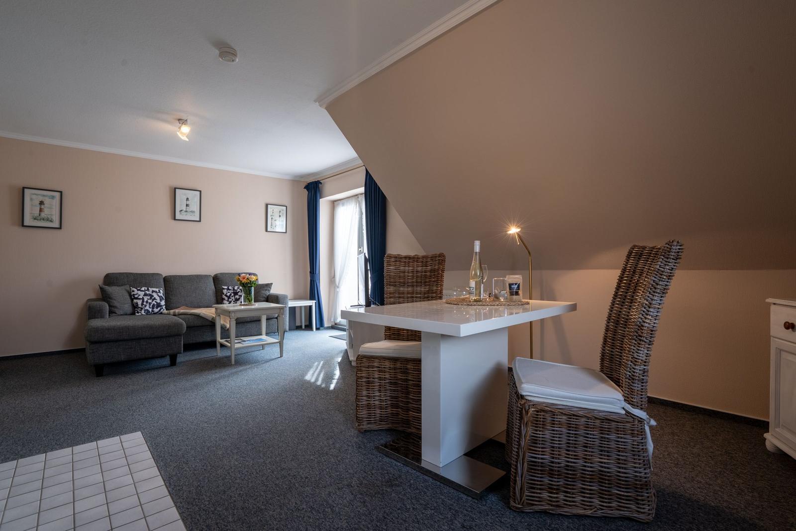 Wohn- und Essbereich mit Sofa, Esstisch und Stühlen unter schrägem Dach.