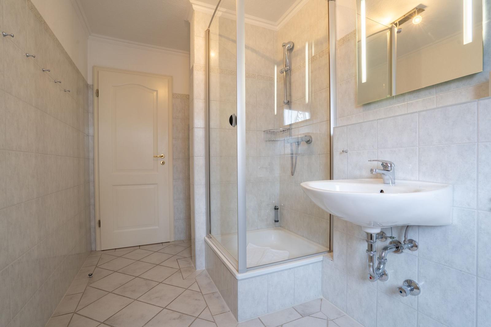 Badezimmer mit Dusche, Waschbecken und Spiegel