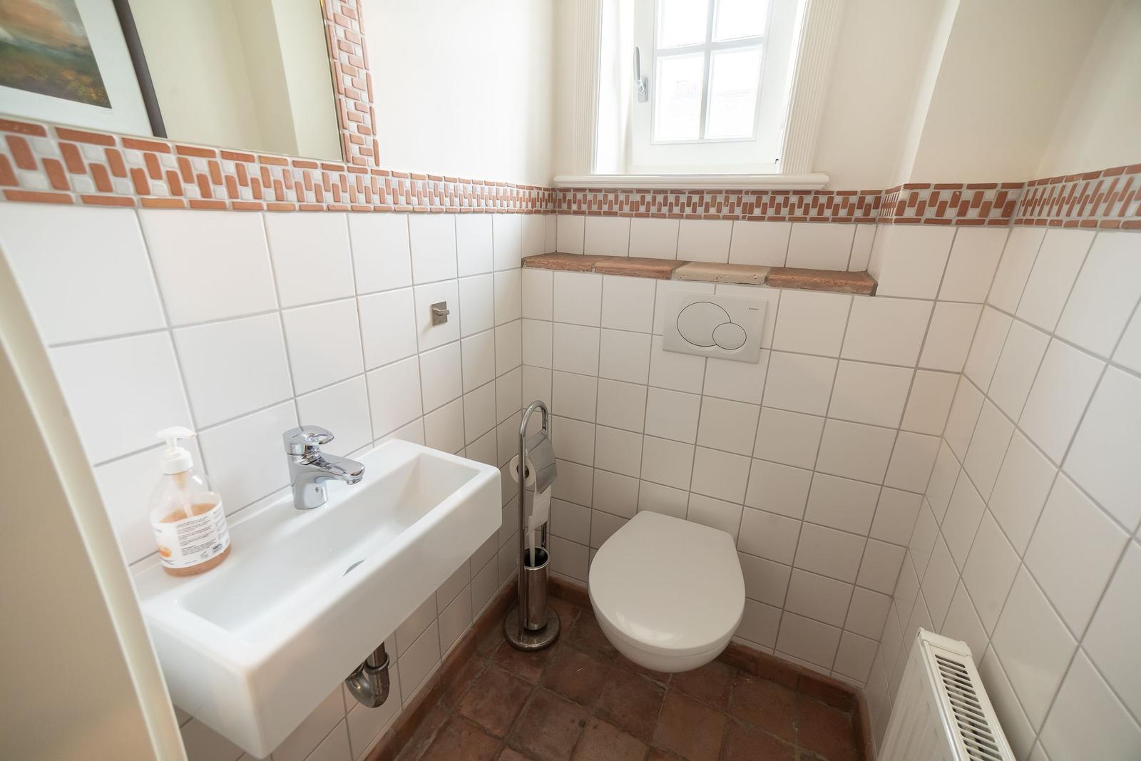 Bathroom with toilet, sink, and window