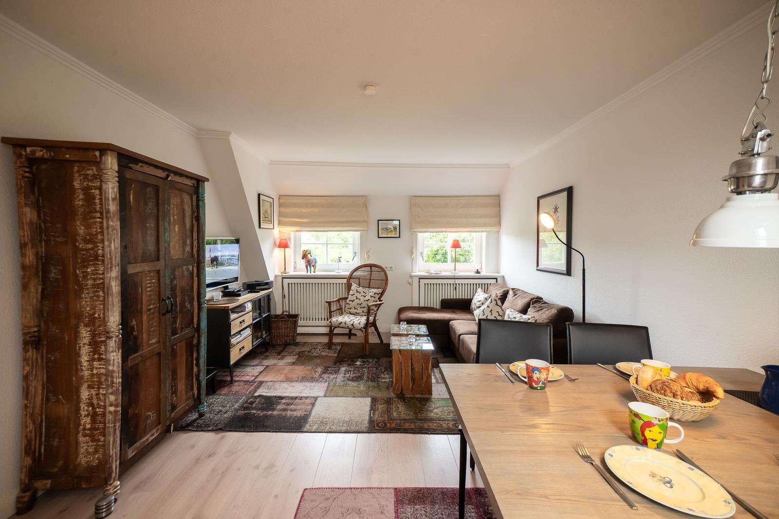Living and dining area with sofa, dining table, and antique cabinet.