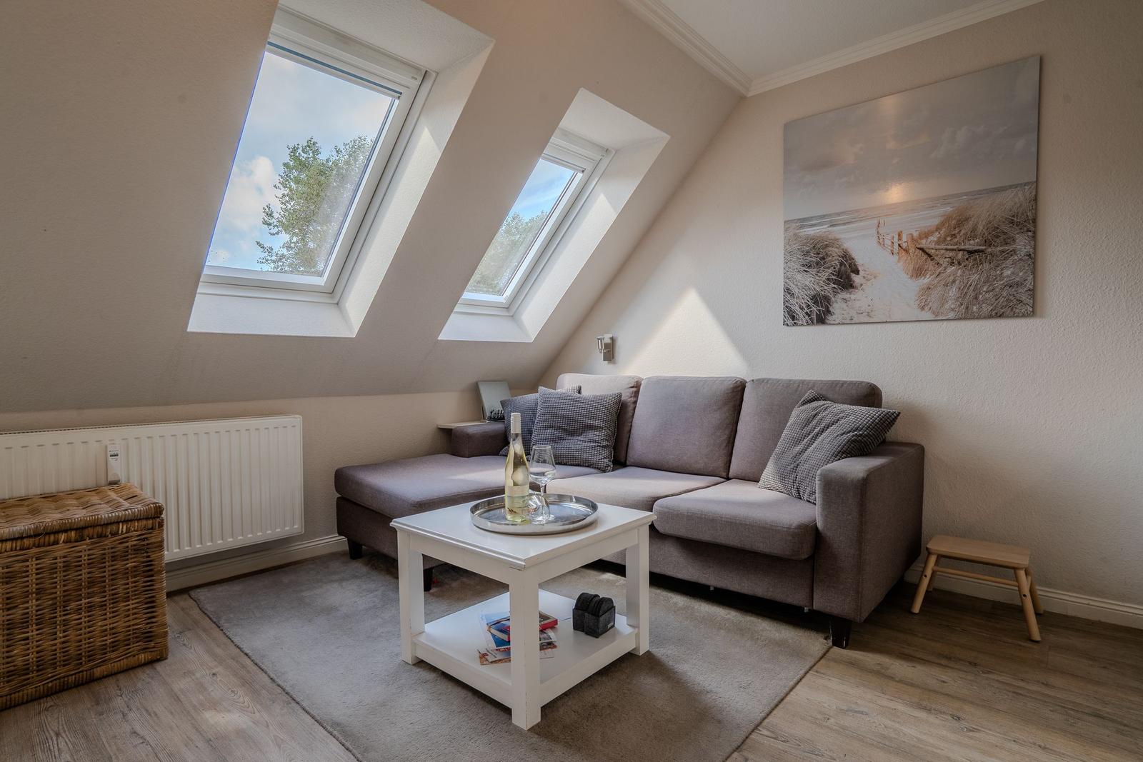 Dachgeschosswohnung mit zwei Dachfenstern, Sofa und Wandbild.