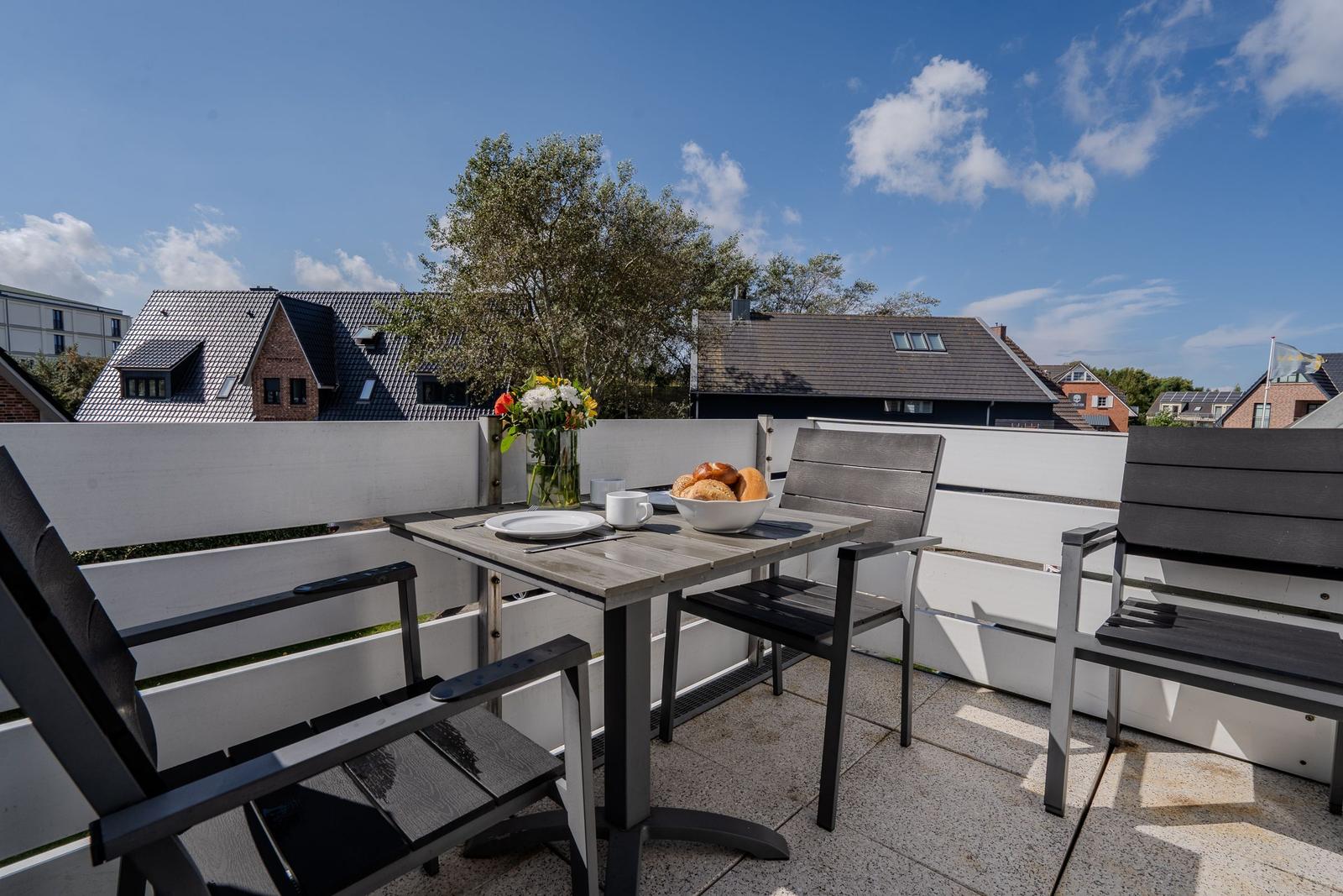 Terrasse mit Tisch, Stühlen und Blick auf Wohnhäuser.