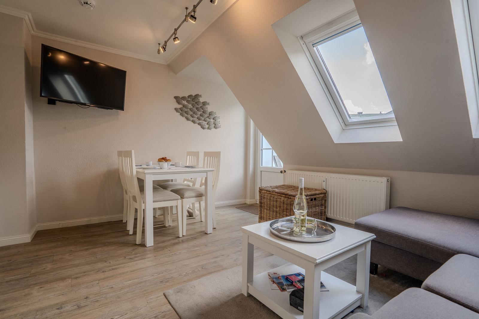 Wohn- und Essbereich mit TV, Tisch, Stühlen und Dachfenster.