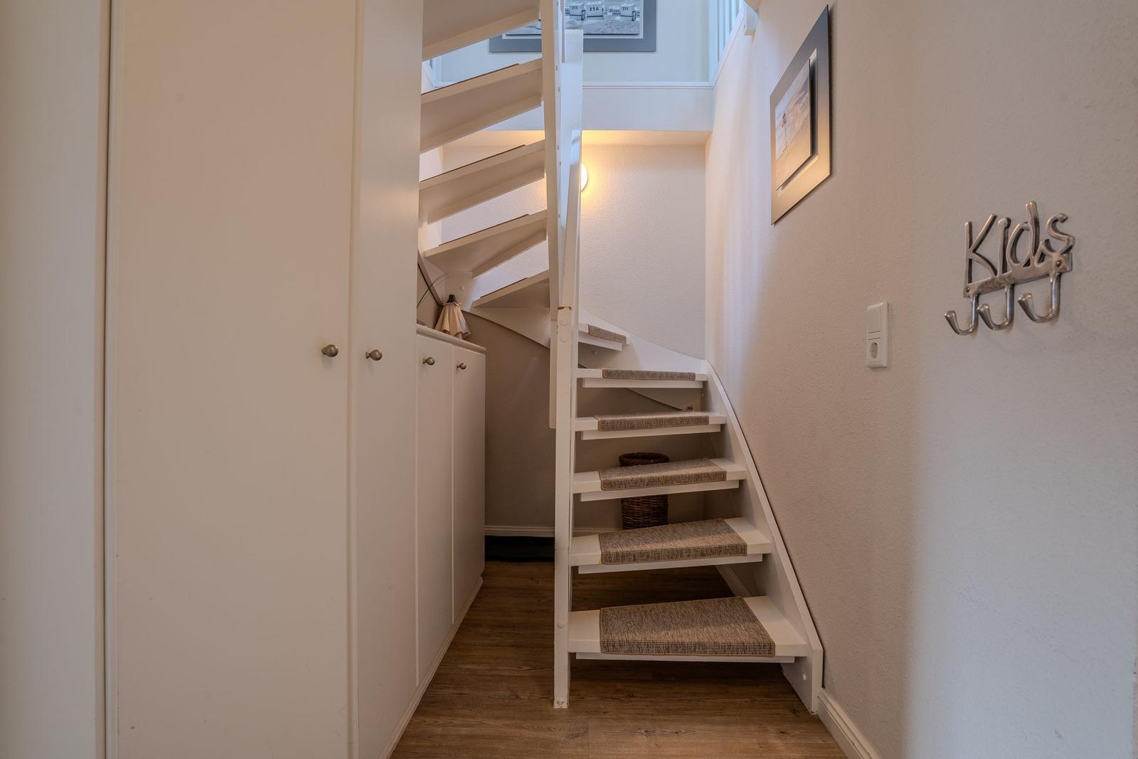 Treppenhaus mit weißer Treppe und Kinderhaken an der Wand