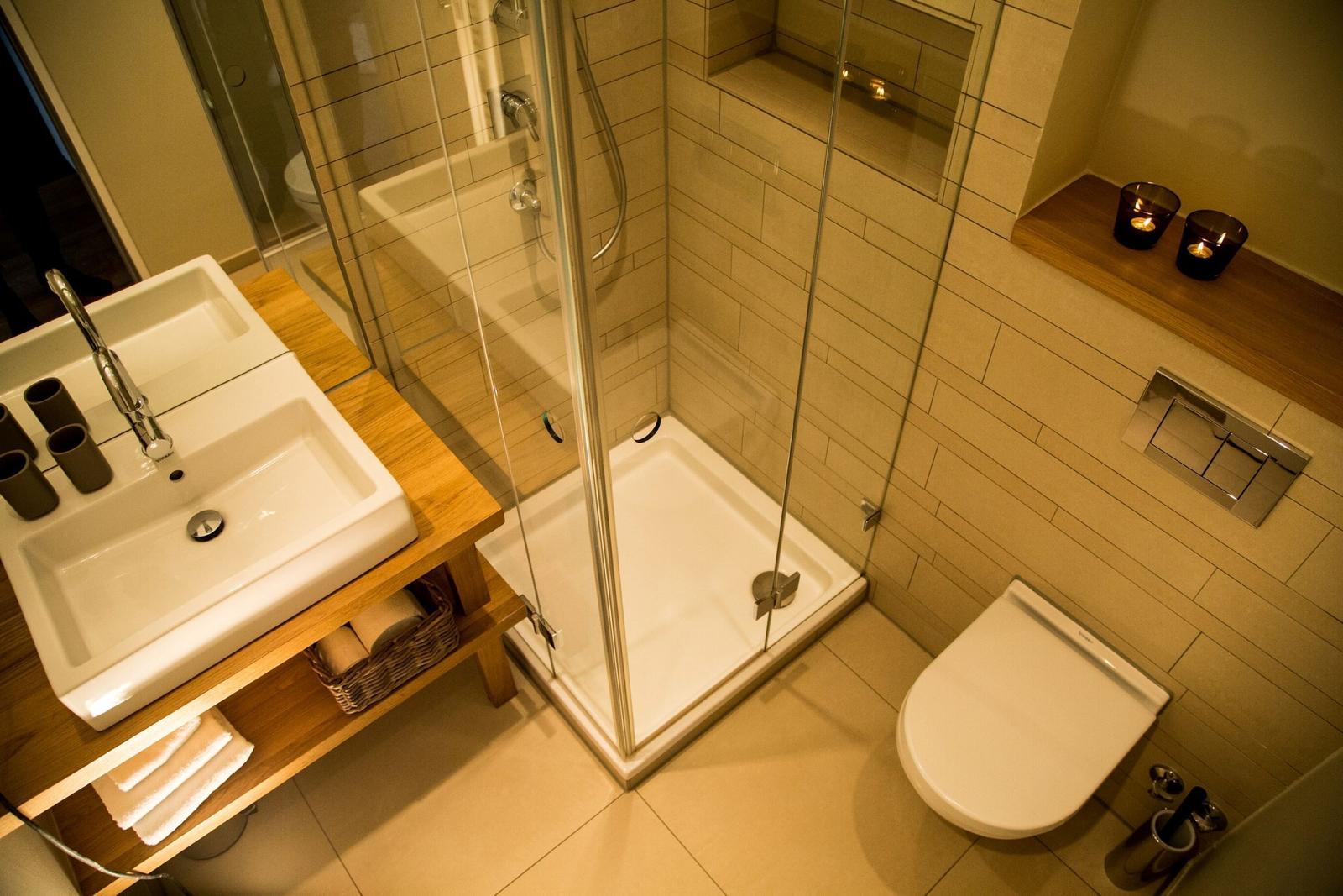 Bad mit Dusche, Waschbecken und Toilette. Holzregal und Kerzen.