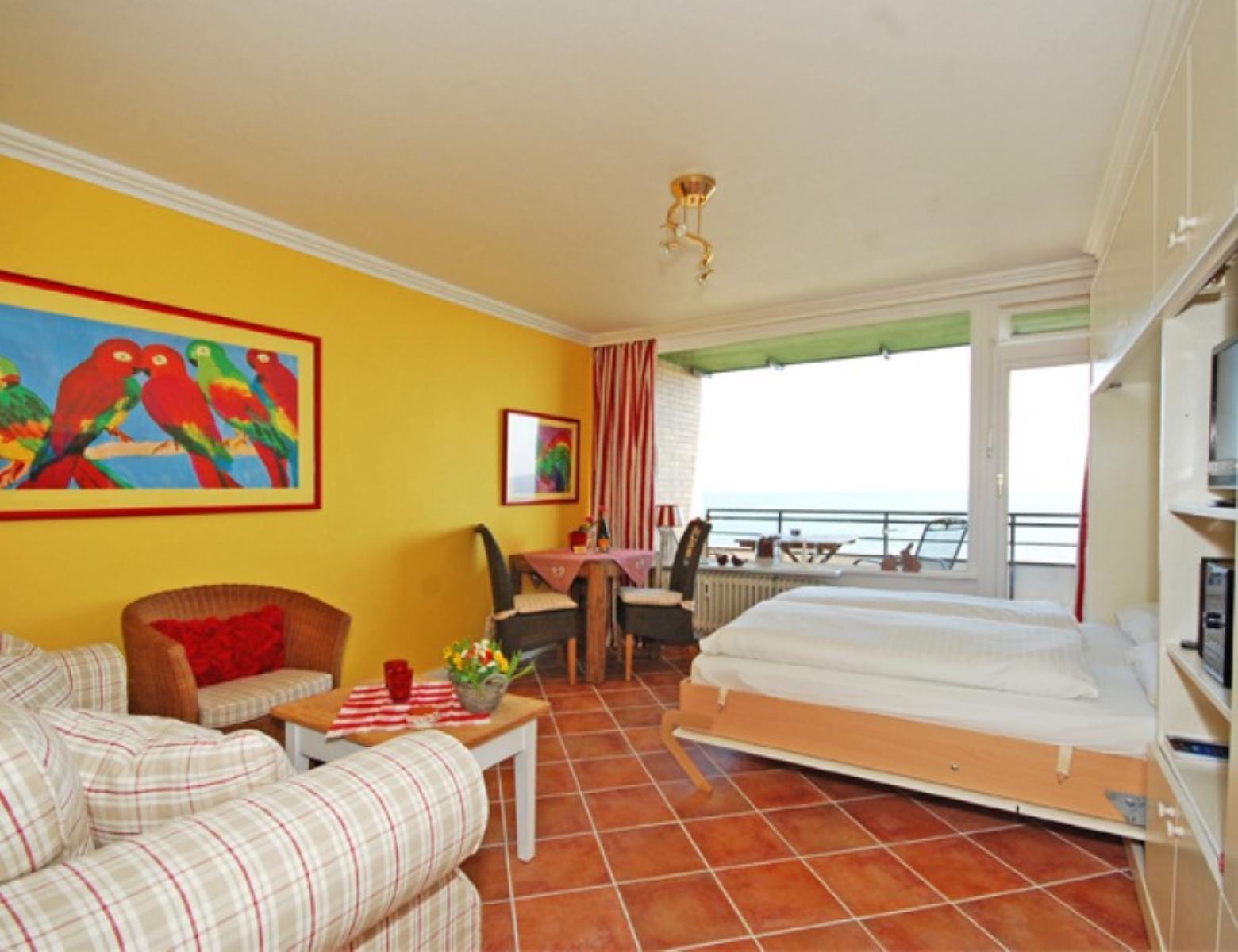 Zimmer mit Bett, Sofa, Tisch und Balkon mit Meerblick.
