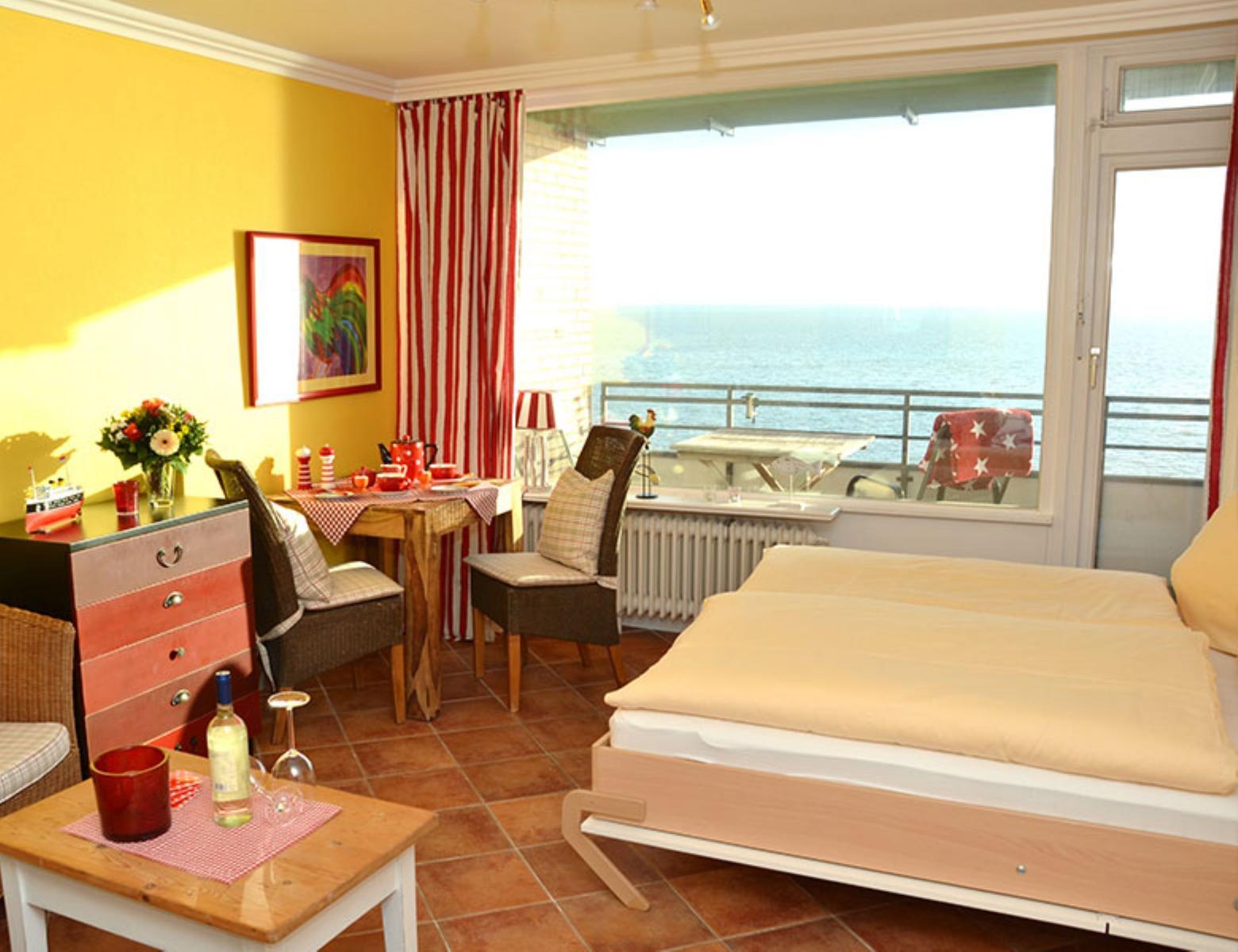 Zimmer mit Bett, Tisch, Stühlen und Meerblick über Balkon