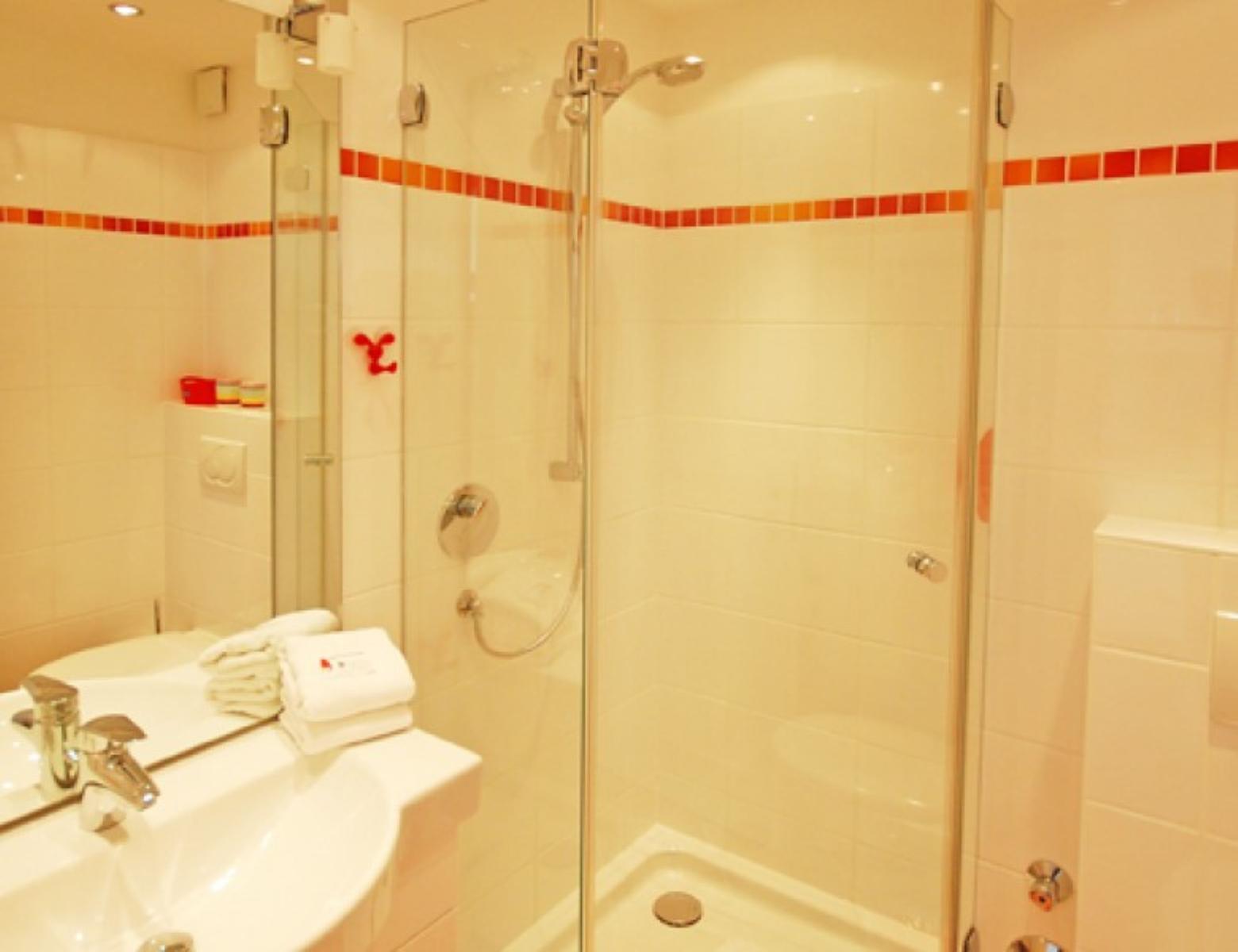 Badezimmer mit Dusche, Waschbecken und Handtüchern