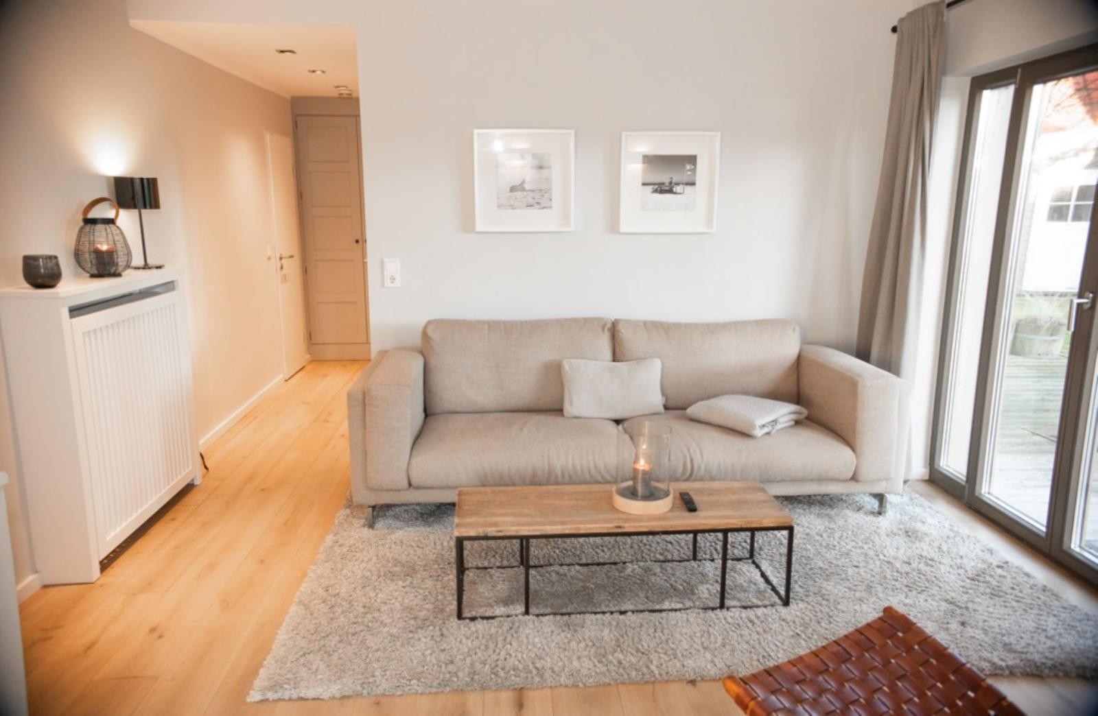 Wohnzimmer mit Sofa, Couchtisch und Schiebetür zur Terrasse.