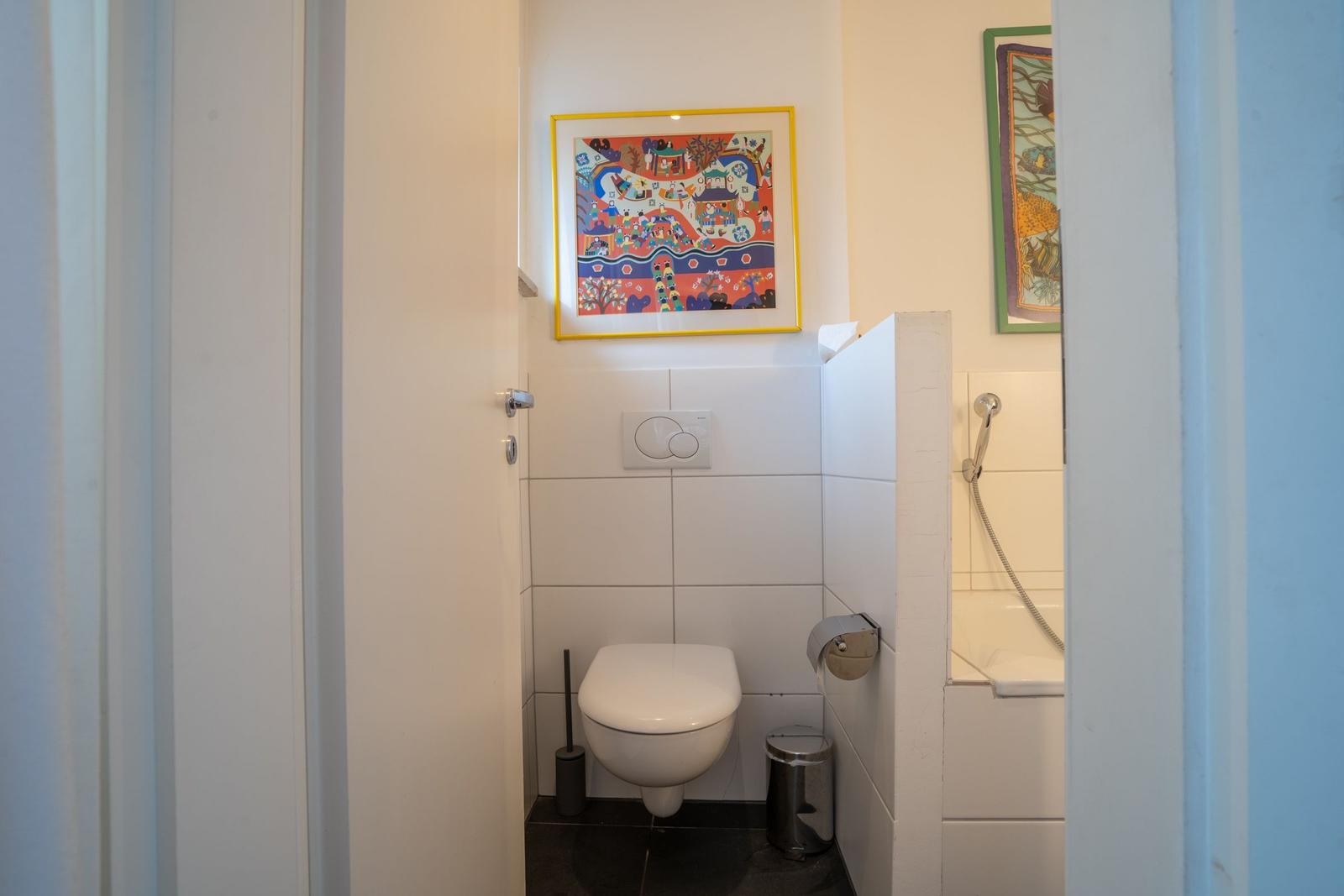 Bathroom with toilet, shower, and wall pictures