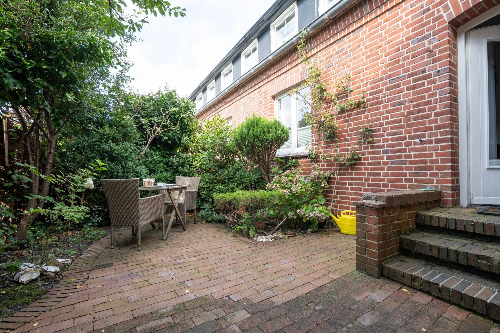 Backyard with table, chairs, plants, and brick wall.