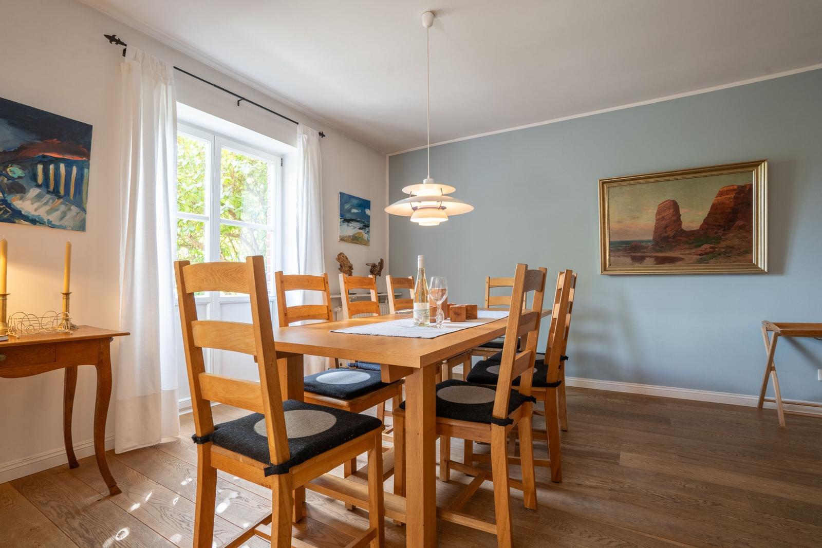 Dining room with wooden table, chairs, and wall paintings.