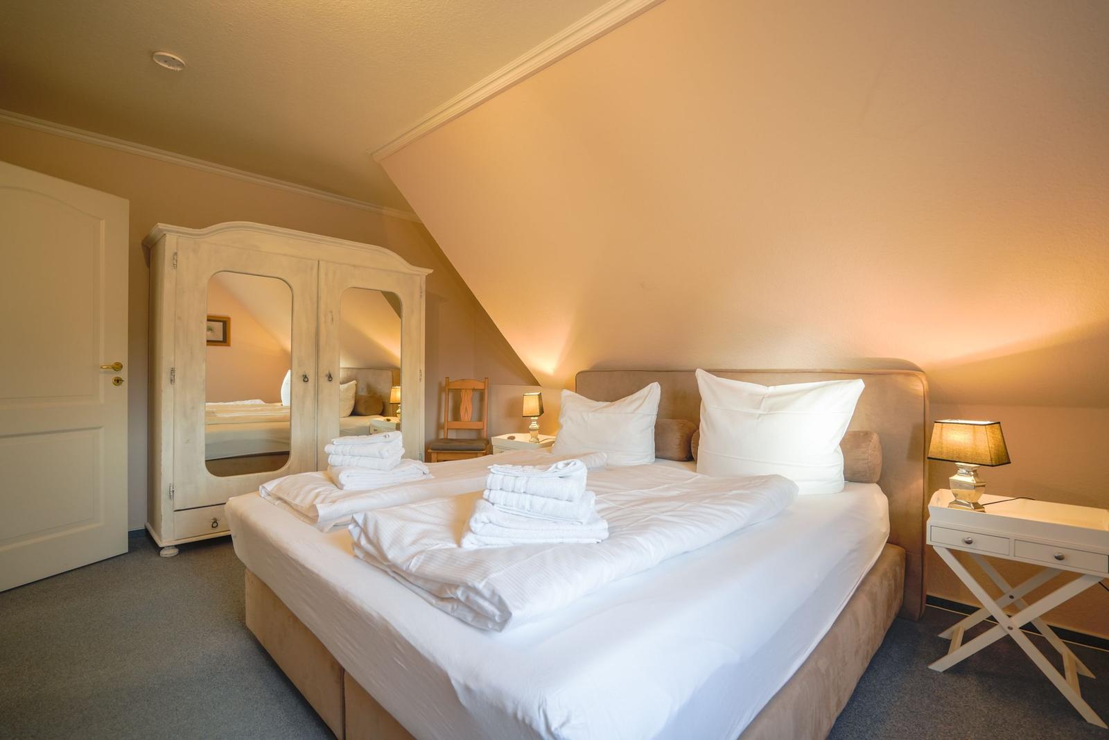 Schlafzimmer mit Doppelbett, Schrank und Nachttisch.