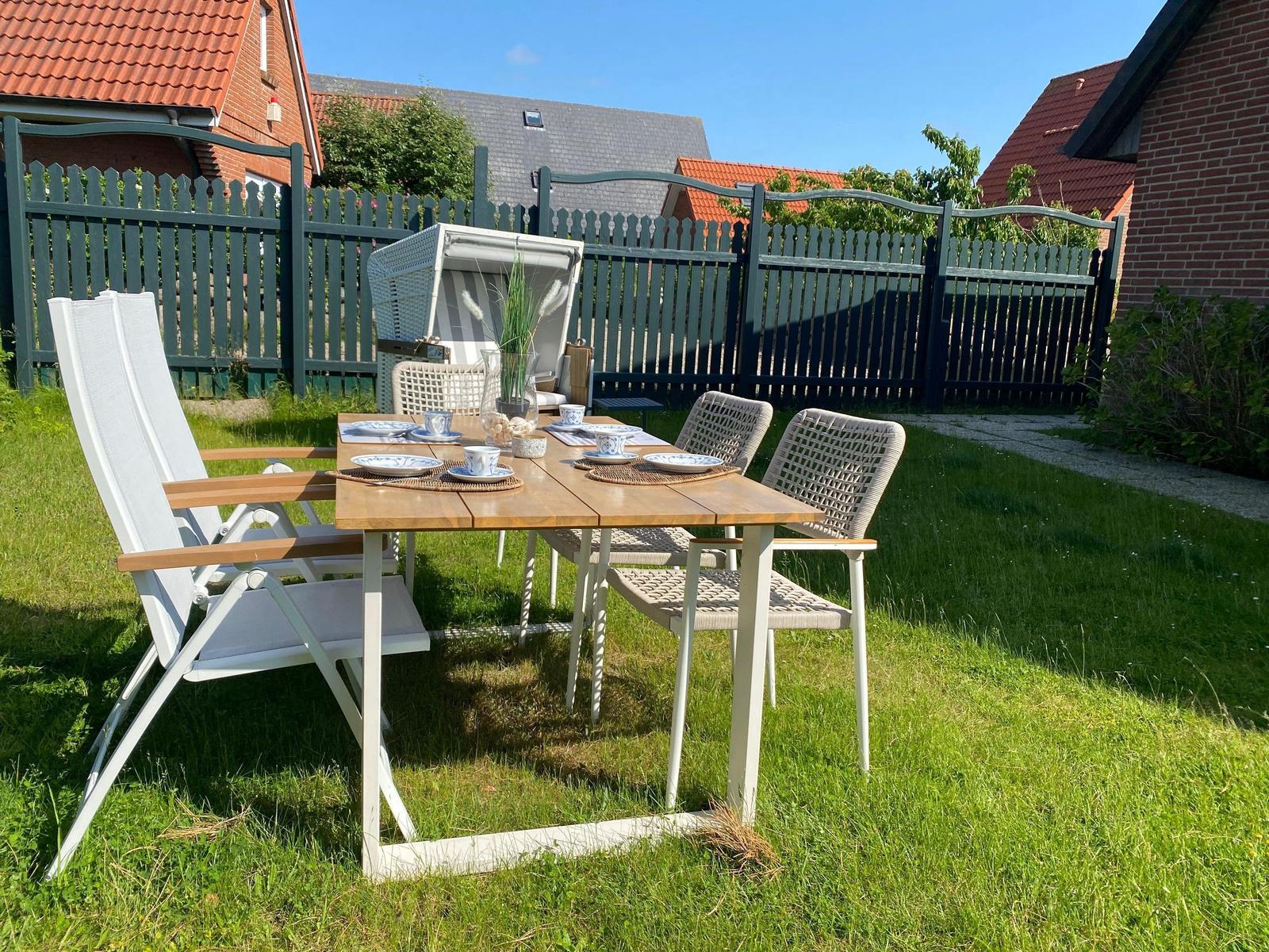 Garten mit Tisch und Stühlen für sechs Personen.