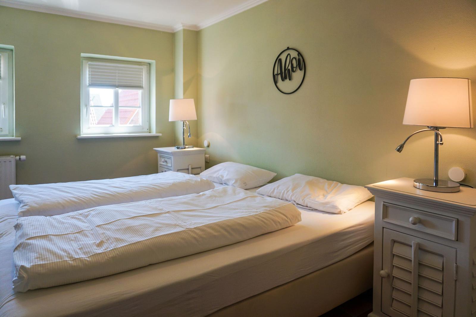 Schlafzimmer mit Bett, zwei Nachttischen und Wanddekoration.