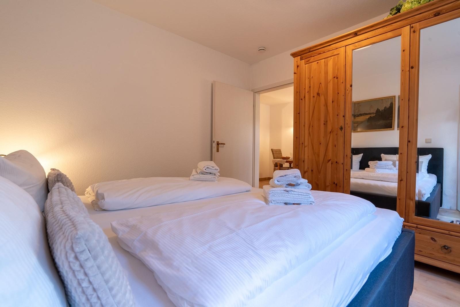 Bedroom with bed, mirrored wardrobe, and towels.