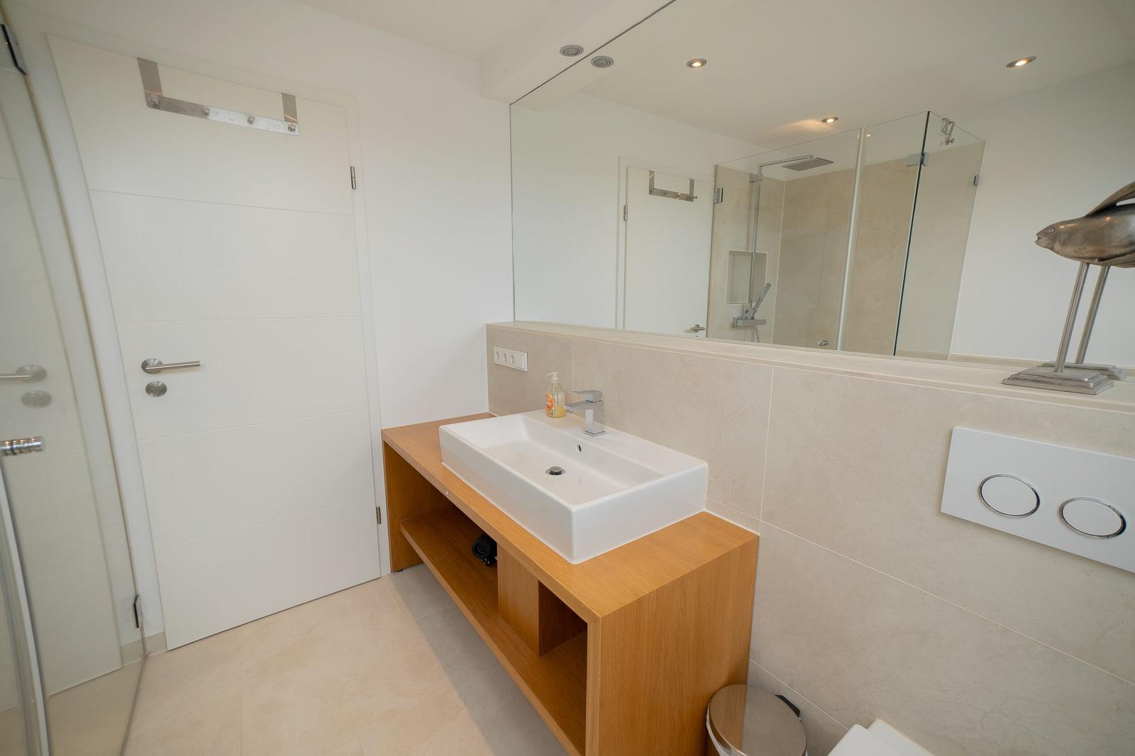 Badezimmer mit Waschbecken, Spiegel und Dusche.