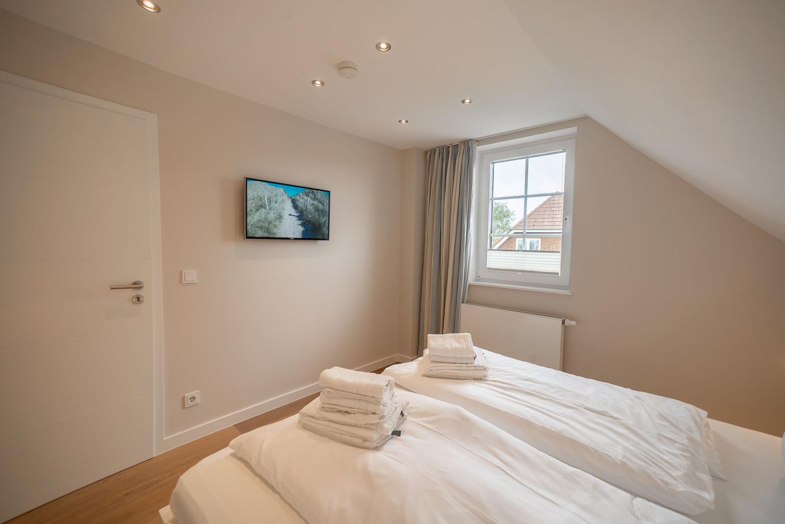 Zimmer mit zwei Betten, TV und Fenster mit Blick auf Dach