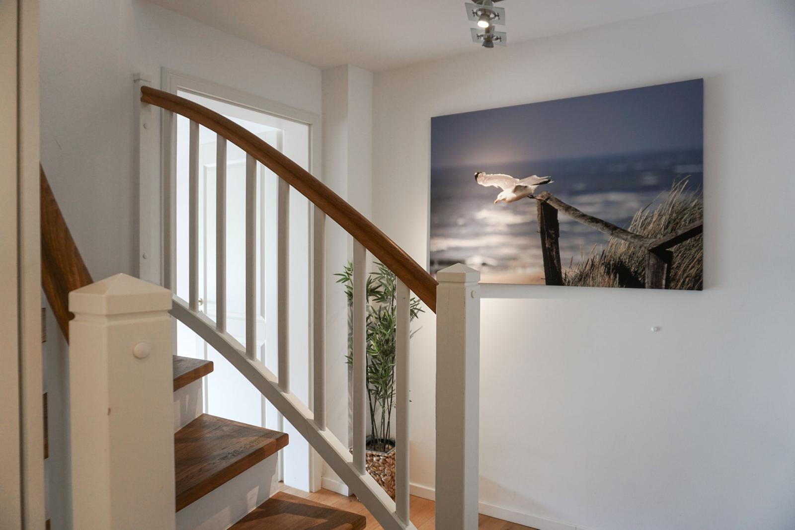 Staircase with wooden handrail and wall picture of a seagull.