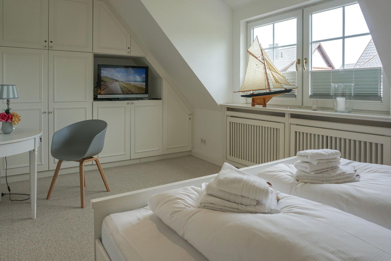 Room with double bed, TV, and window with sailboat model.