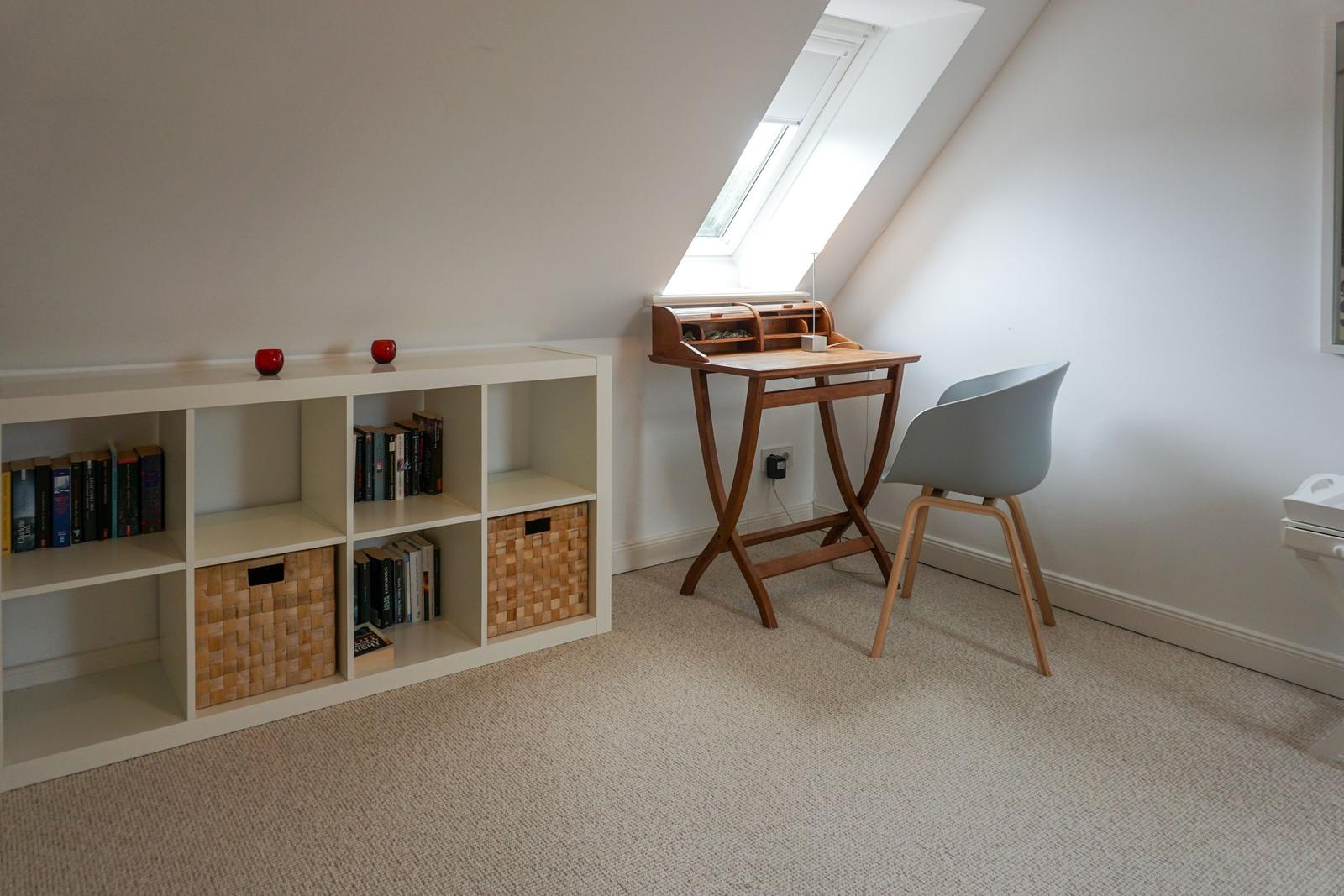 Bedroom with desk, bookcase, and skylight.
