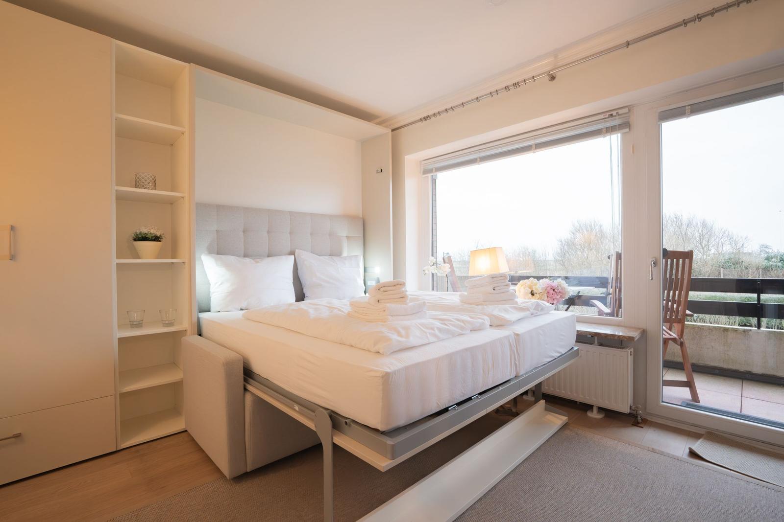 Bedroom with bed, closet, and balcony view.