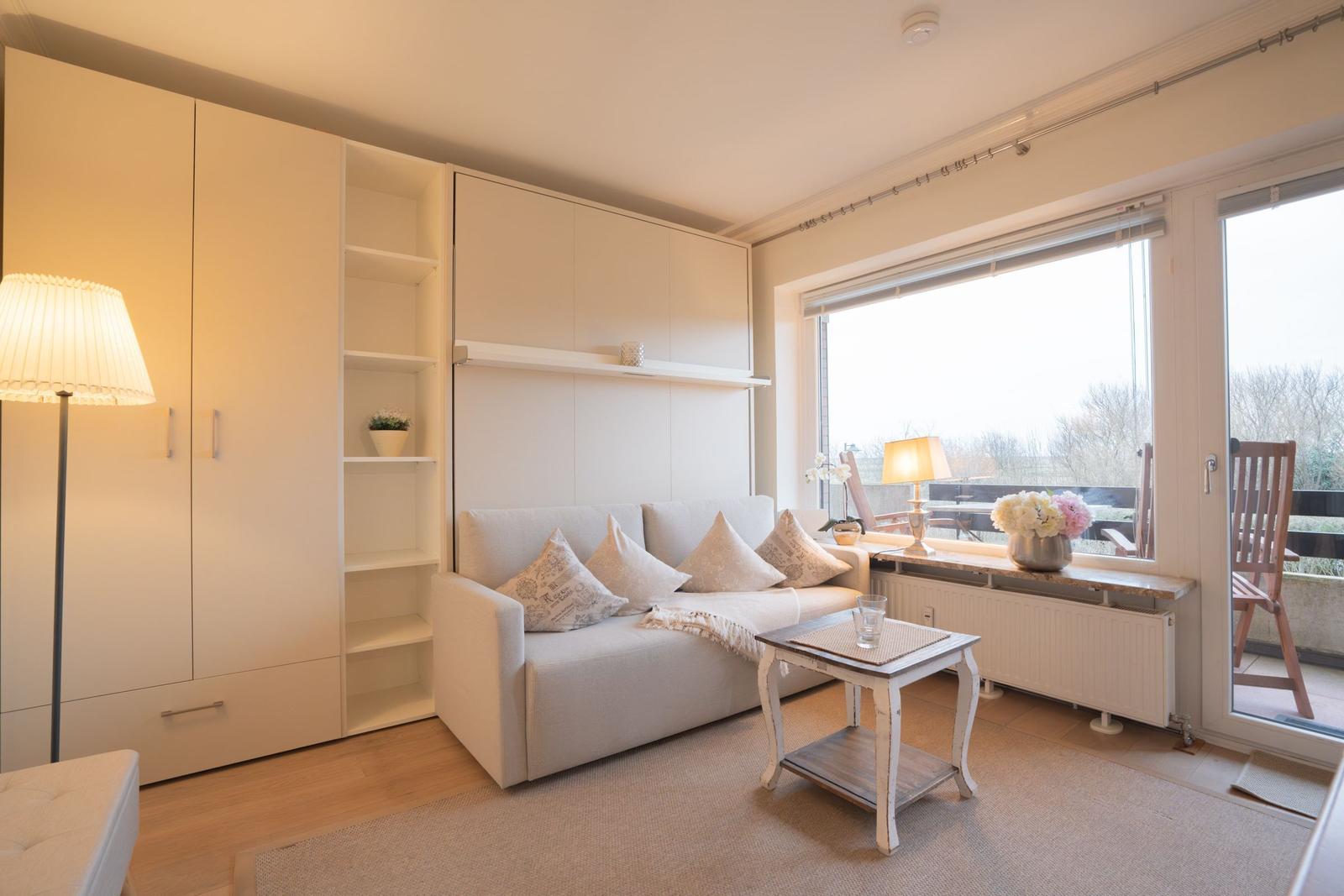 Living room with sofa, sideboard, and view of balcony.