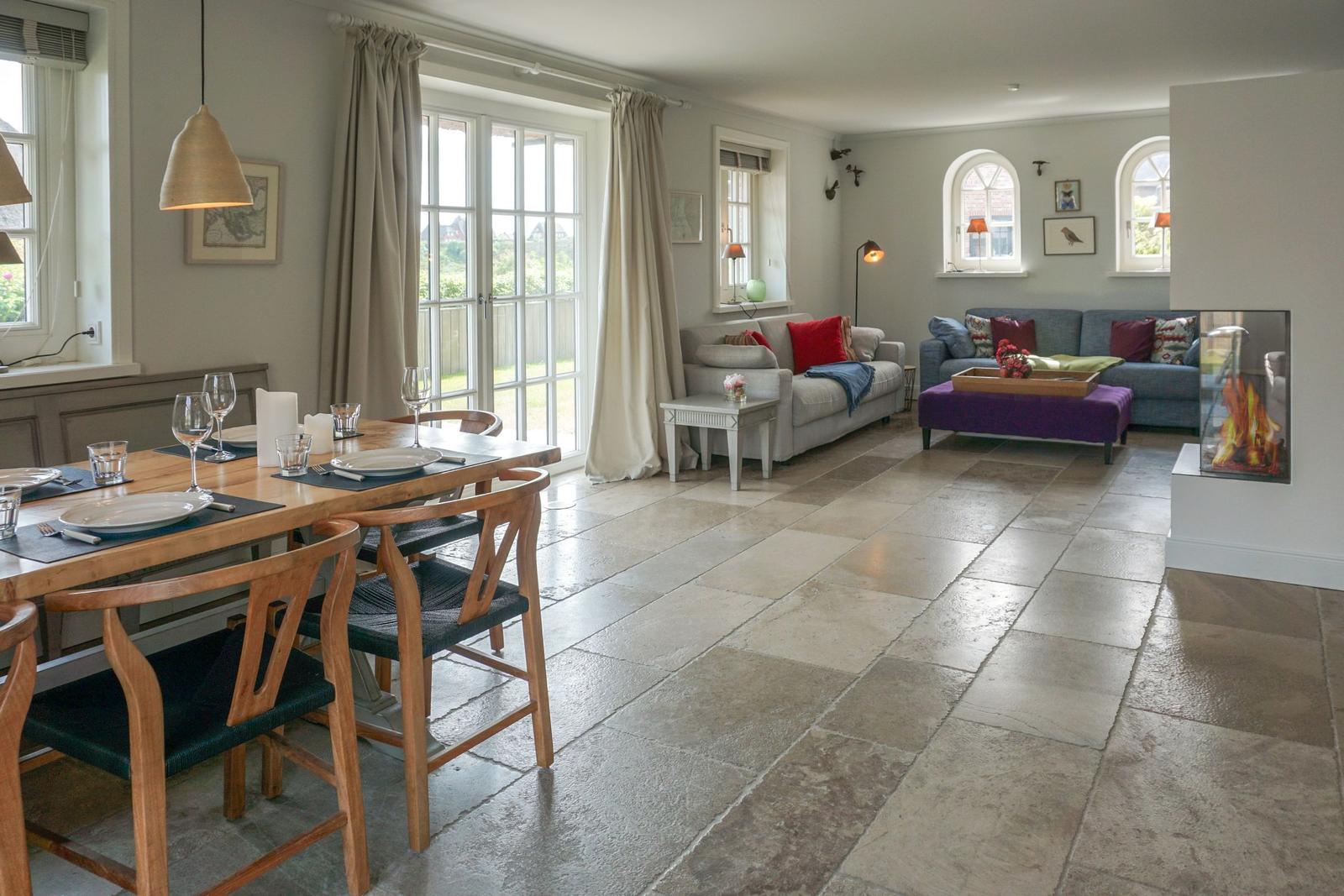 Large living and dining room with stone floor and modern fireplace.