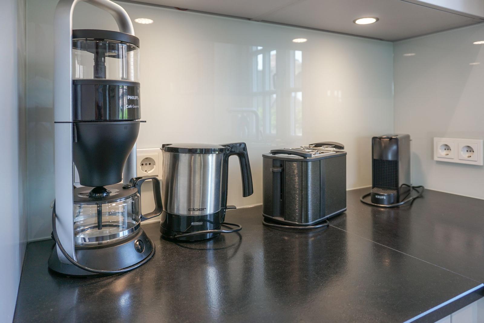 Kitchen counter with coffee maker, kettle, toaster, and coffee machine.