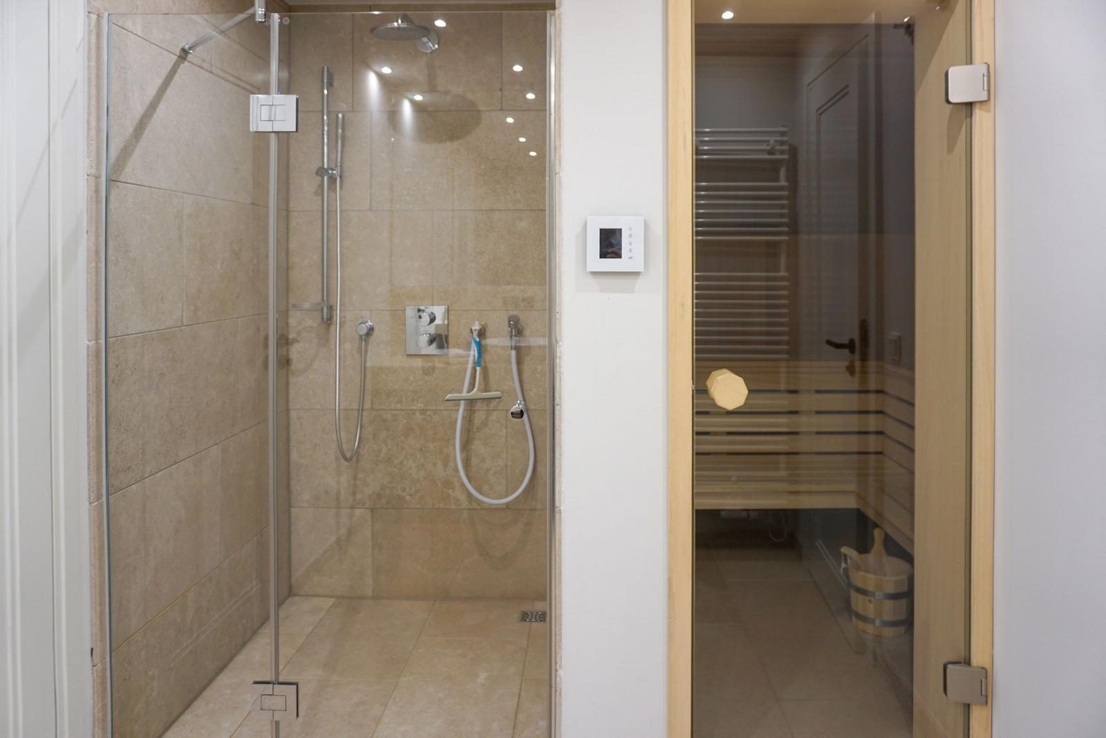 Shower with shower head and sauna with wooden bench