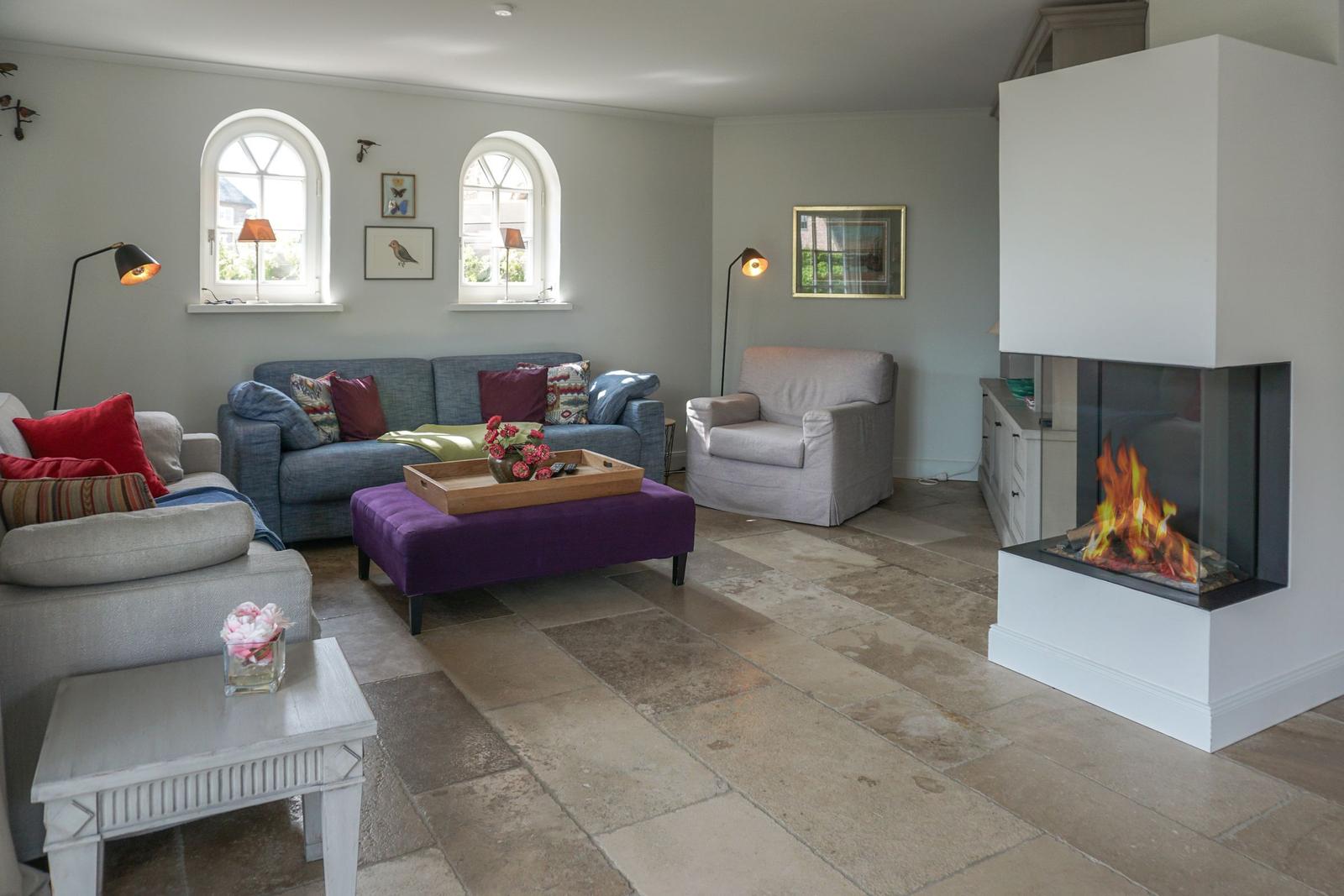 Living room with fireplace, sofa, armchair, and stone floor