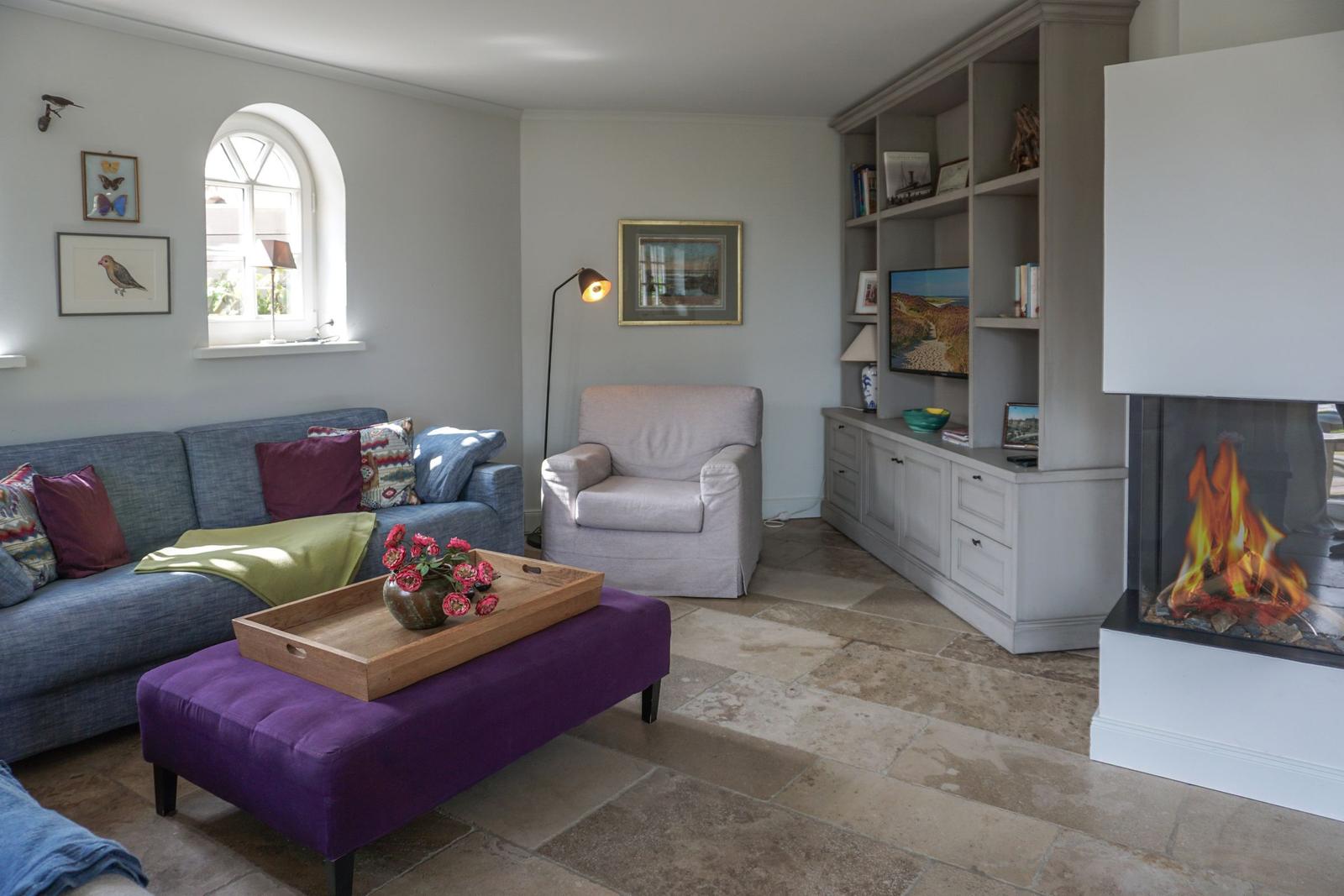 Living room with sofa, armchair, fireplace, and bookcase.