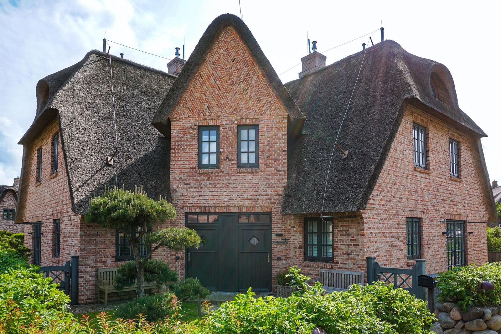 A two-story house with thatched roofs and red brick walls.