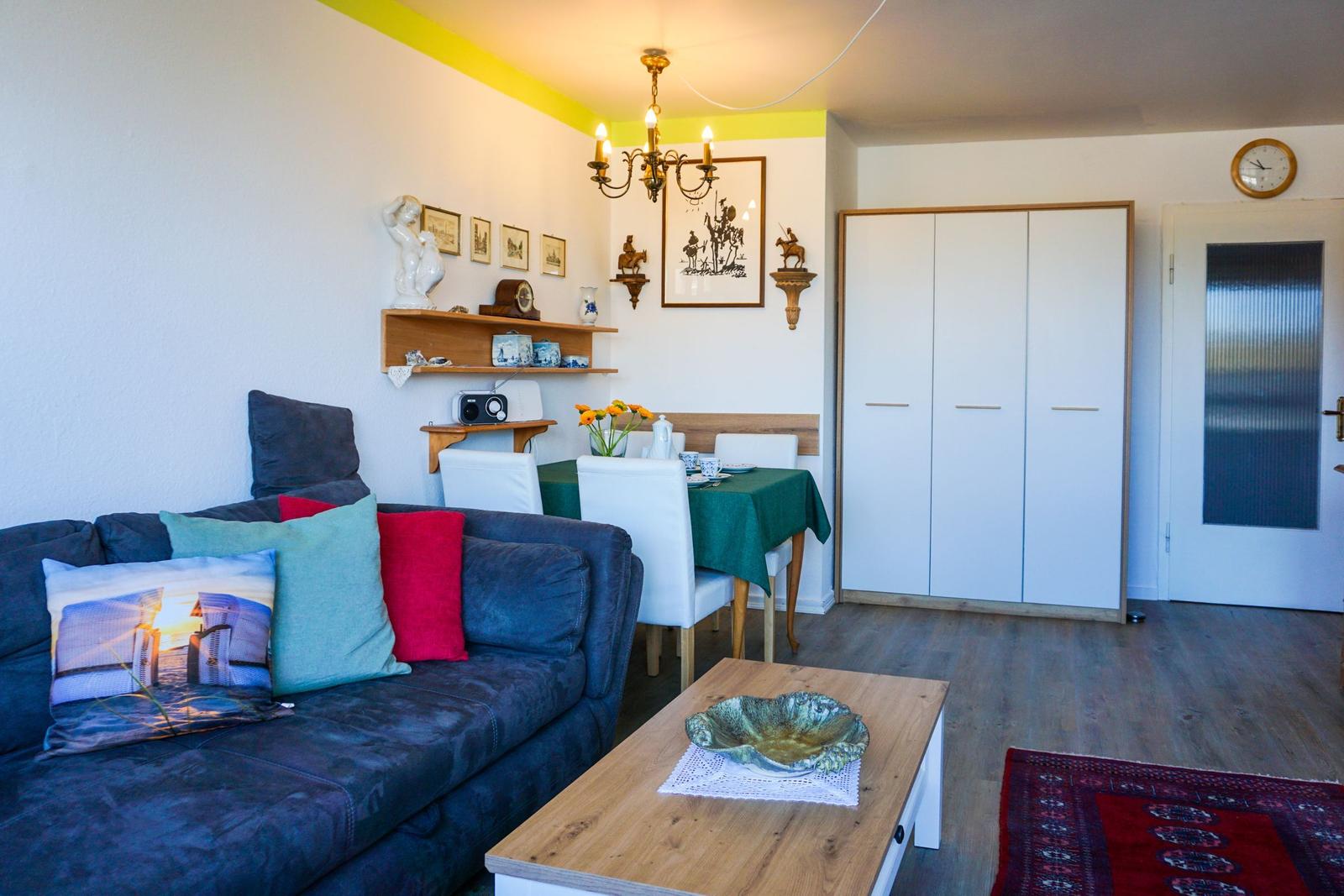 Wohn- und Essbereich mit Sofa, Tisch und Schrank.