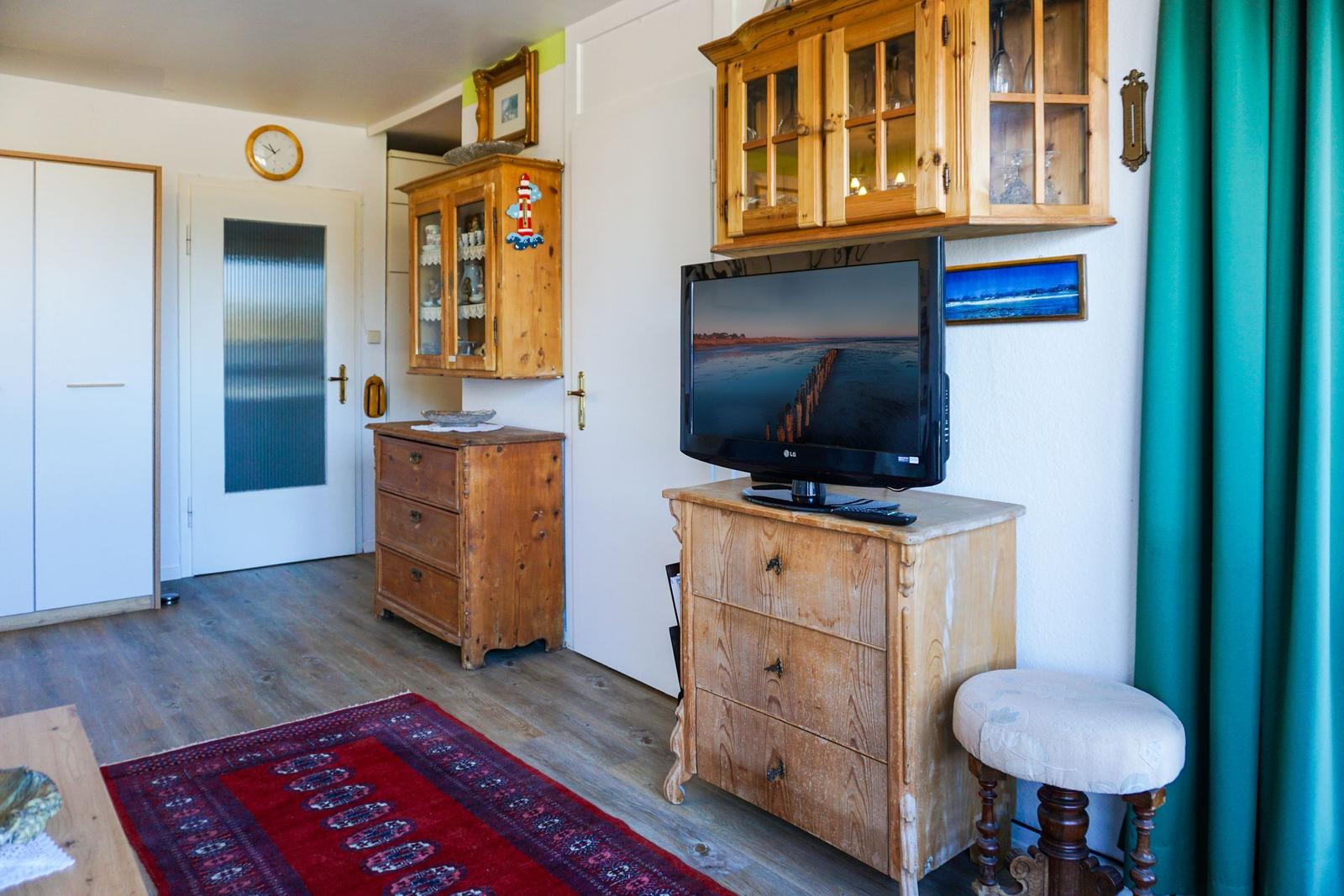Wohnzimmer mit Holzmöbeln, Fernseher und Teppich