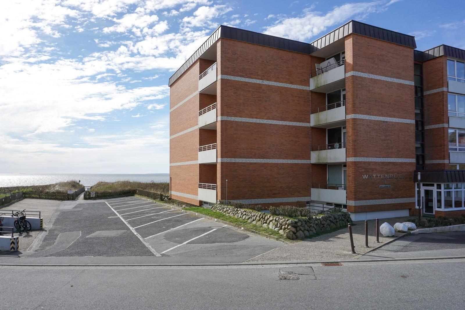 Rotes Backsteingebäude mit Balkonen und Parkplatz. Blick aufs Meer.