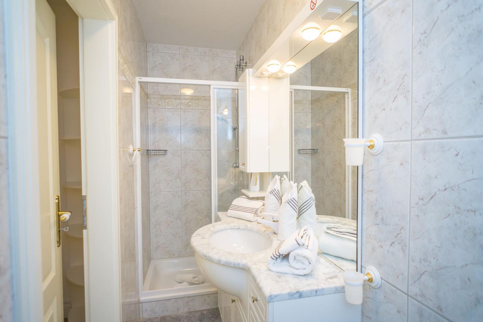 Badezimmer mit Dusche, Waschbecken und Spiegelschrank