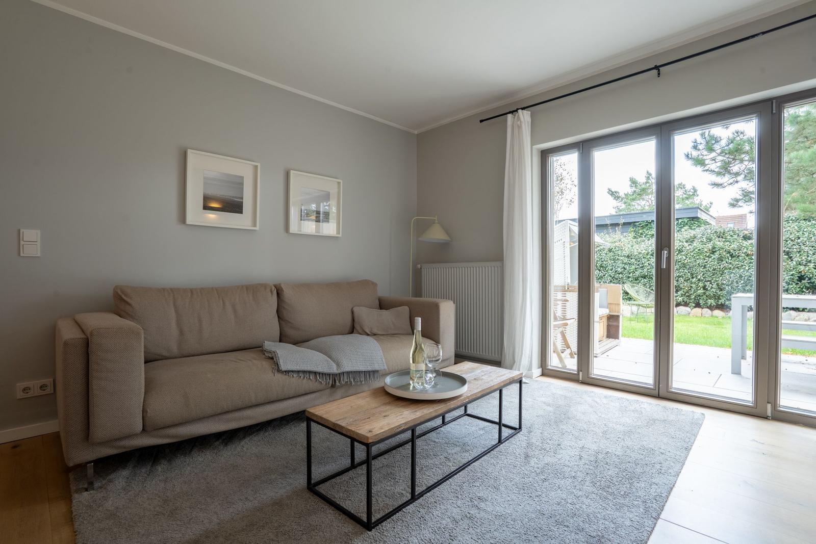 Wohnzimmer mit Sofa, Couchtisch und Terrassentür.