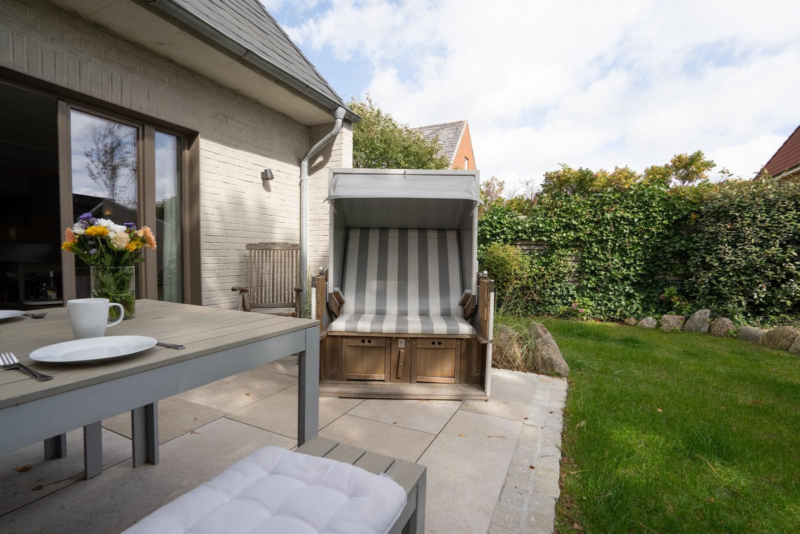 Terrasse mit Esstisch, Strandkorb und Grünfläche