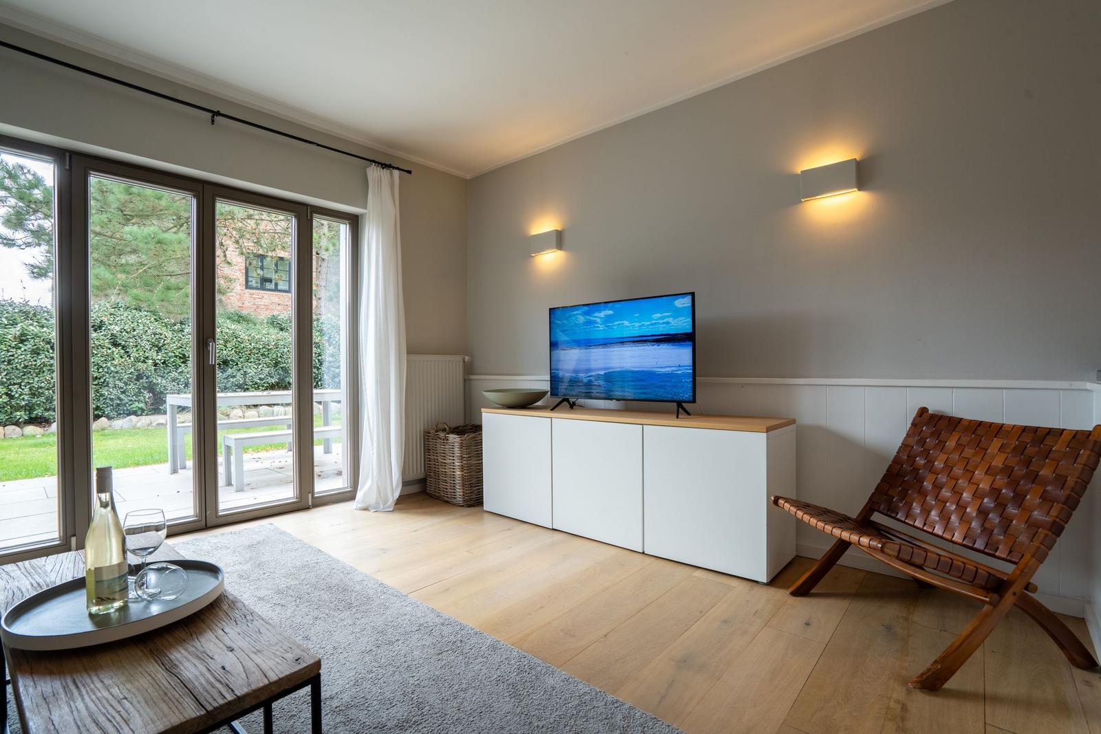 Wohnzimmer mit Fernseher, Sessel und Blick auf Garten