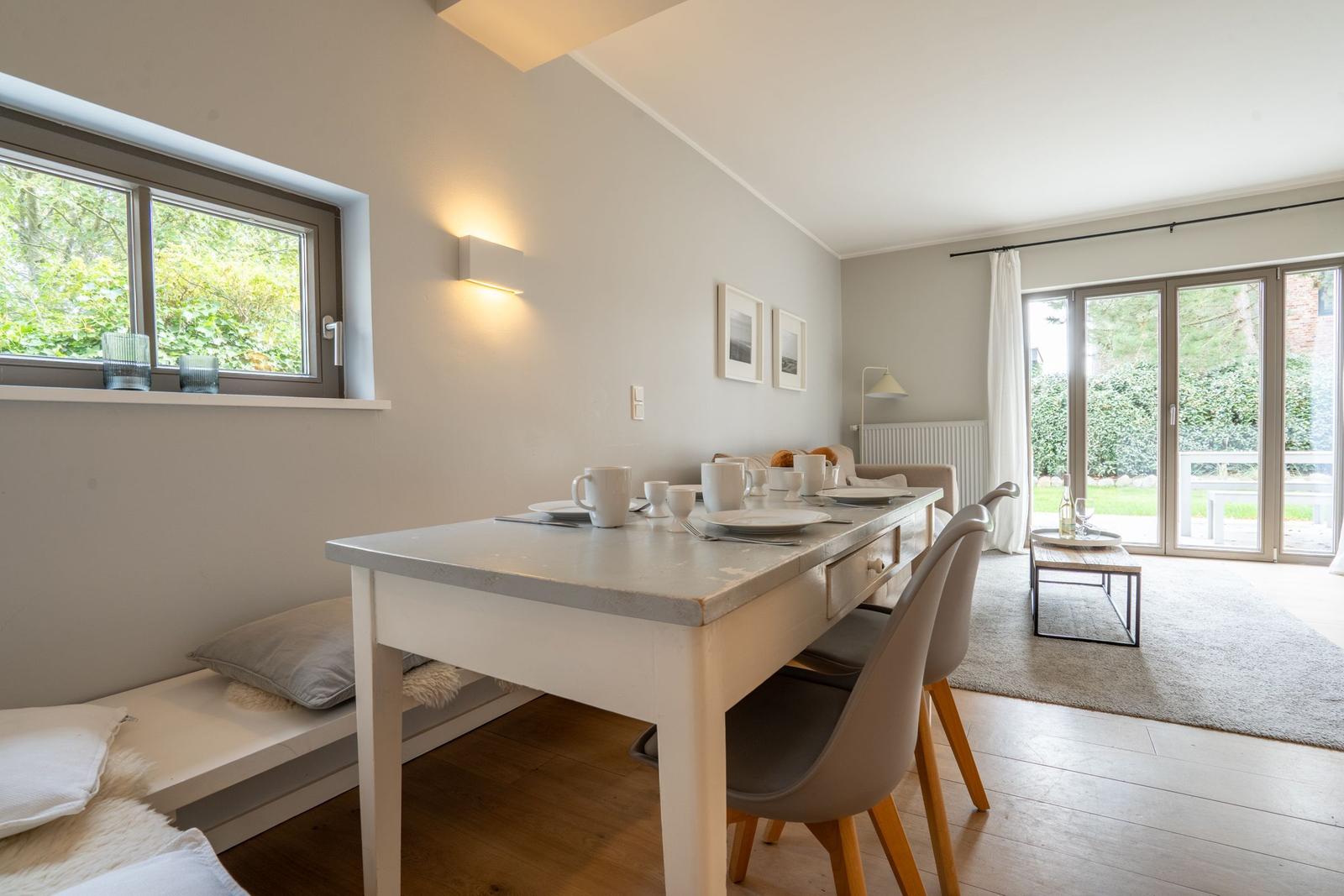 Essbereich mit Tisch, Stühlen und Fenster. Durchgang zur Terrasse mit Glasfront.